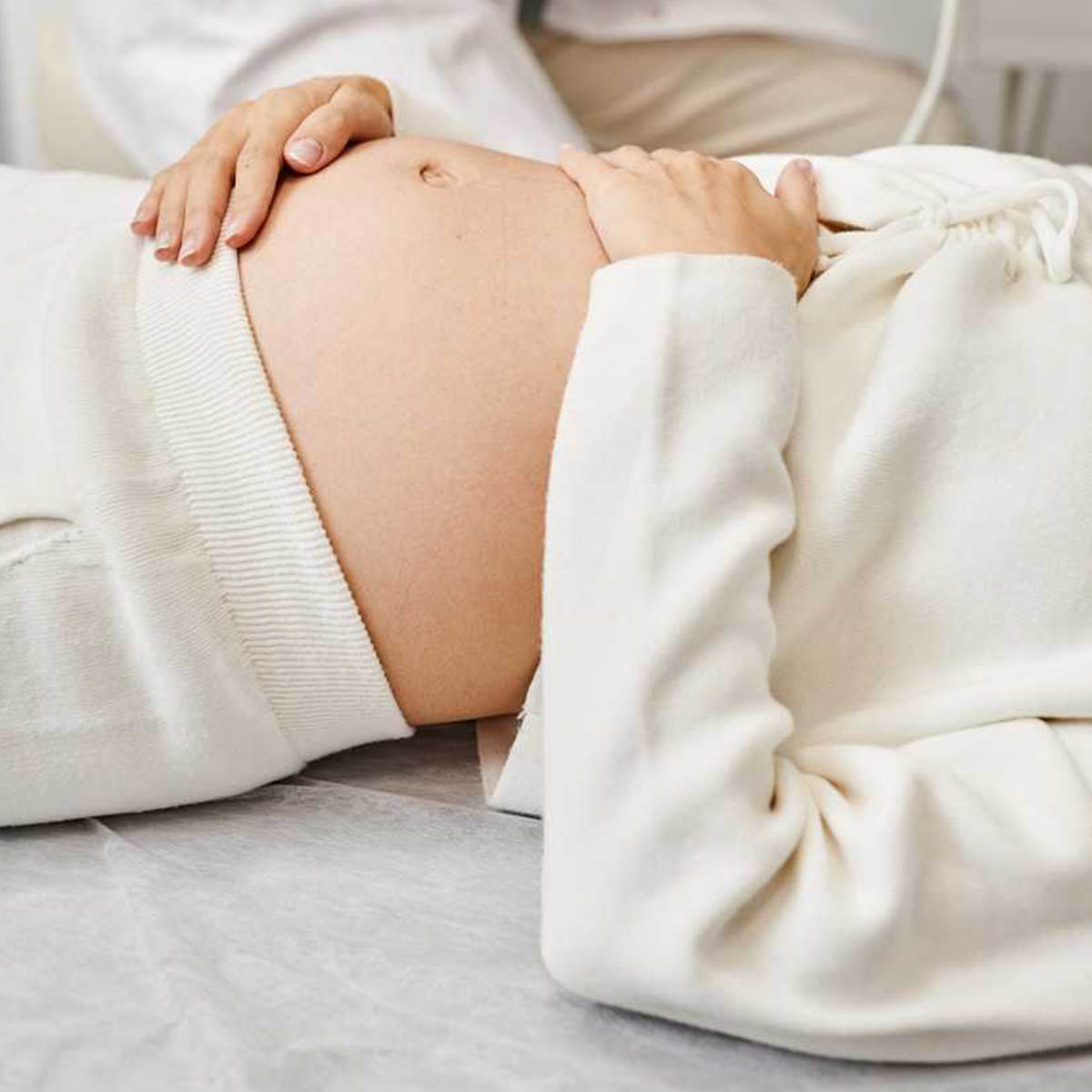 A pregnant woman lays on a bench awaiting acupuncture therapy.