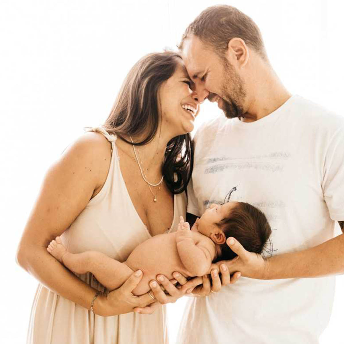 A young man and a woman share a moment of serenity while cradling their newborn child.