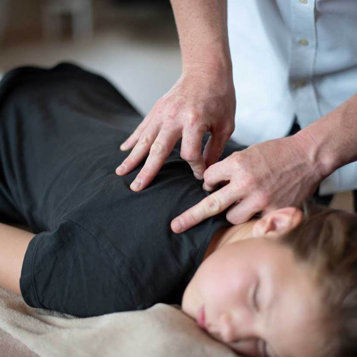 A chiropractor applies treatment to a young woman.
