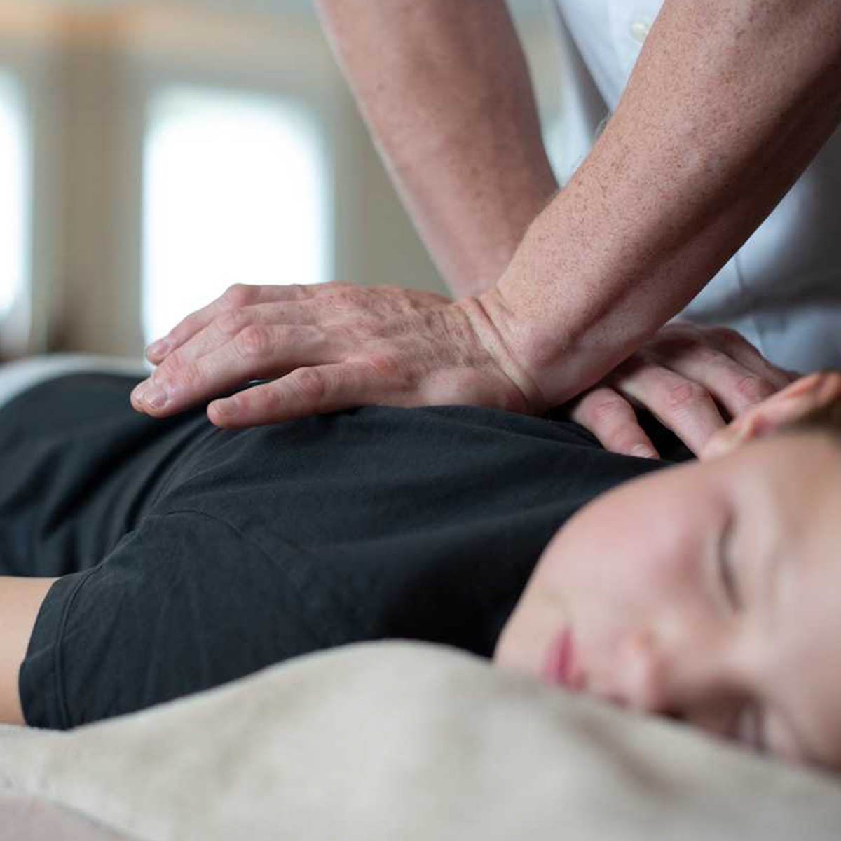 A chiropractor applies treatment to a young woman.