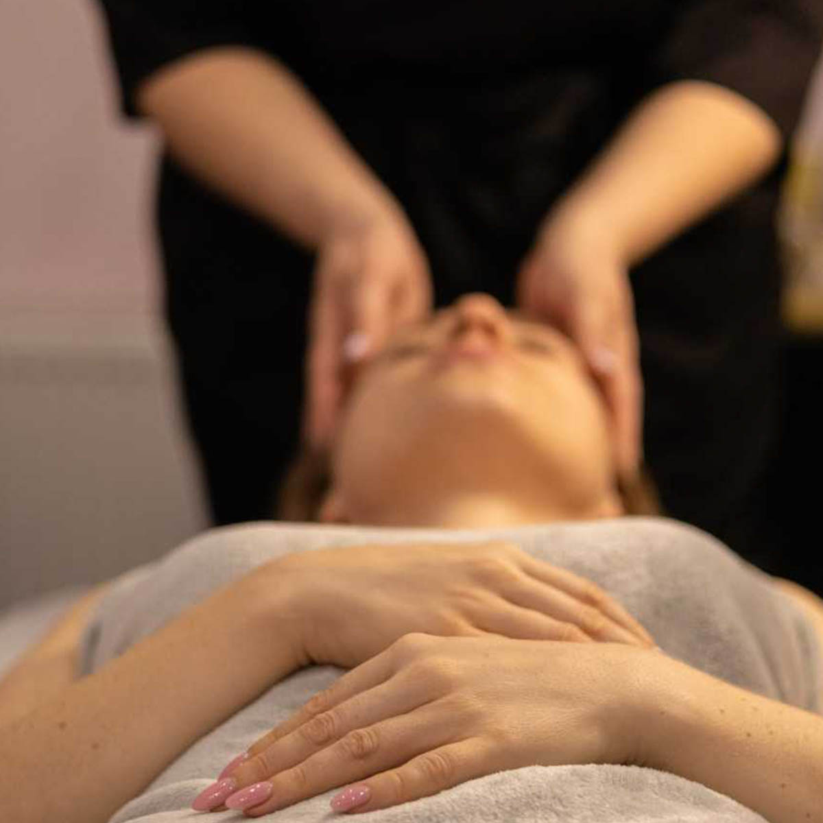Hands apply gentle pressure to a woman laying on a table.