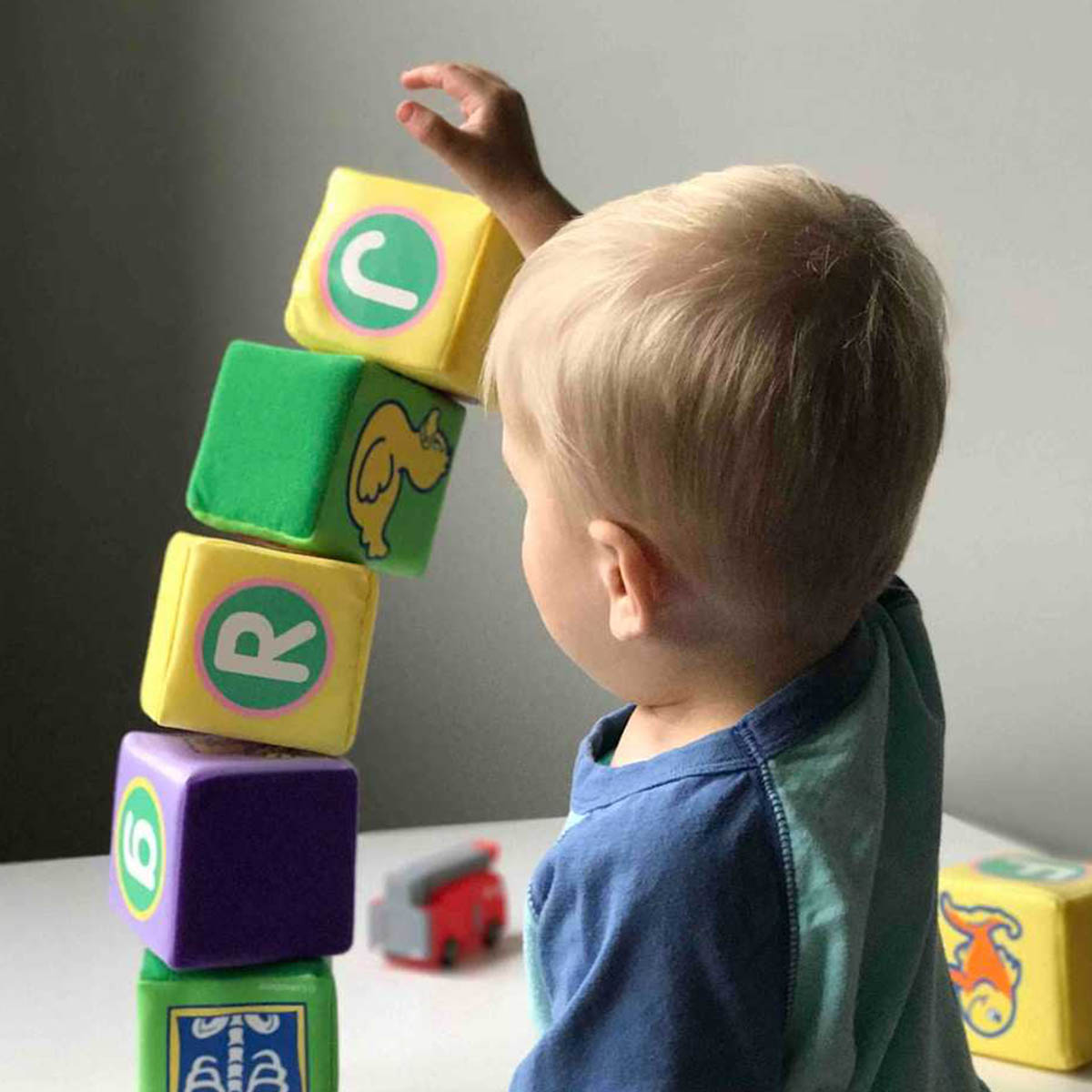 A child plays with a stack of letter bricks. It's just about to fall over!