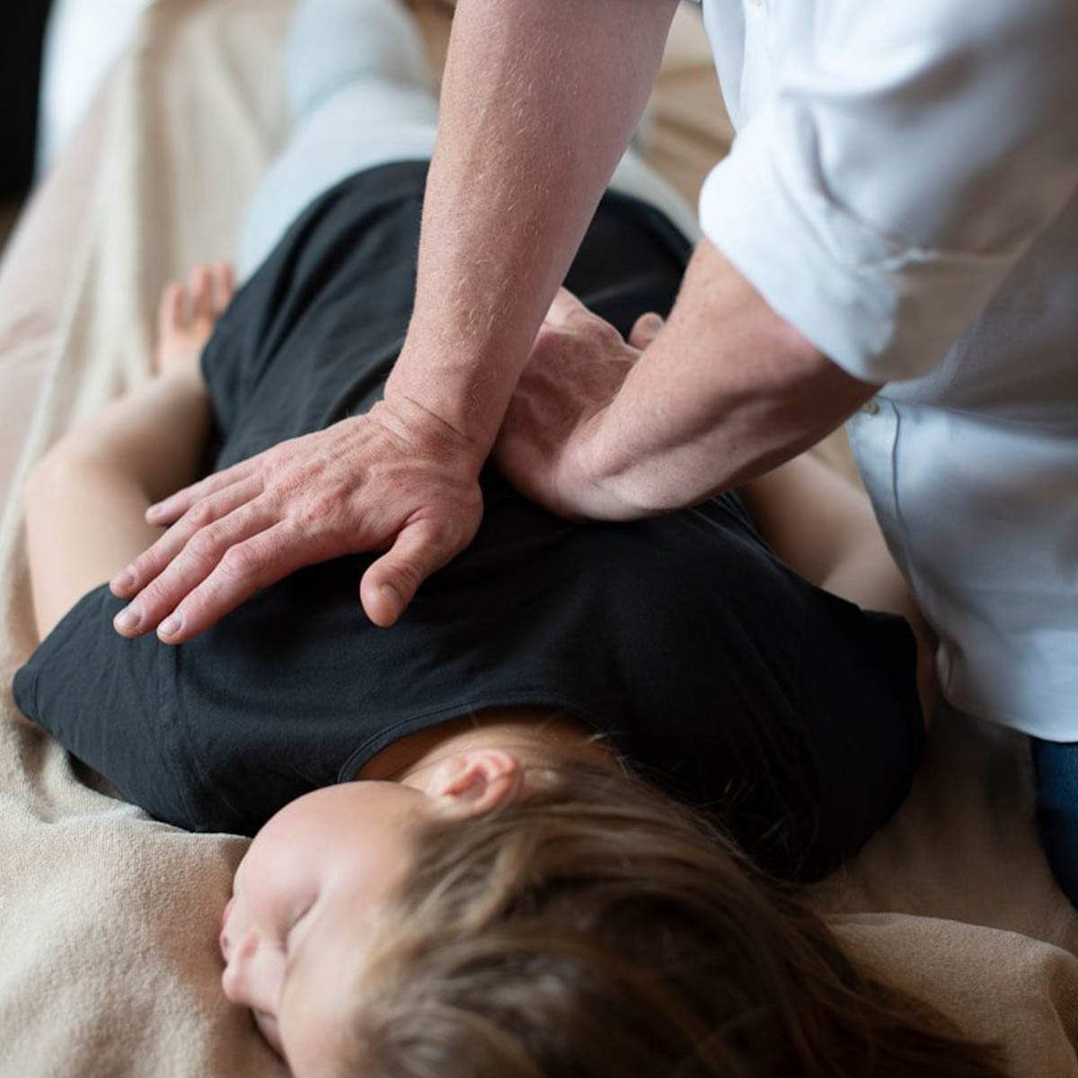 A chiropractor applies pressure to a patient suffering from shoulder pain.