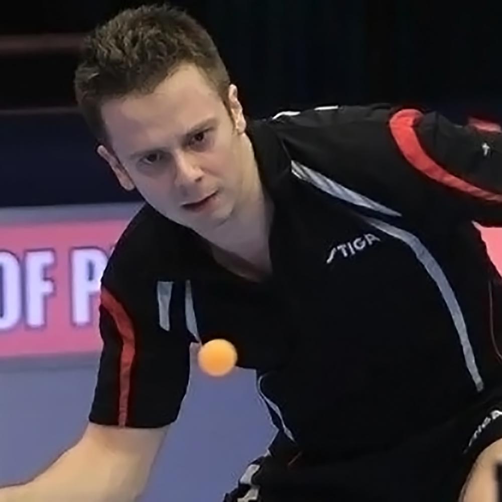 A table tennis player returns a ping pong ball in a match.