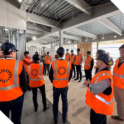 A group of people in construction vests taking a factory tour.