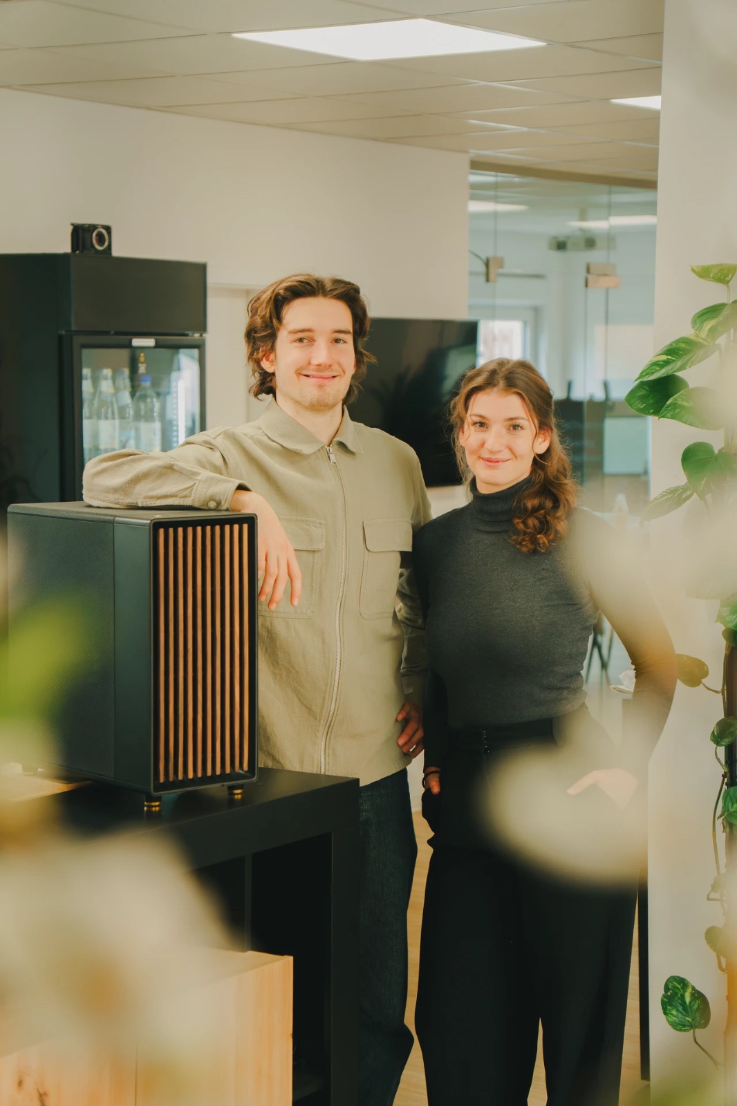 Zwei Mitglieder des Mindspace-Teams im Büro neben einem KI-Server mit Holzfront