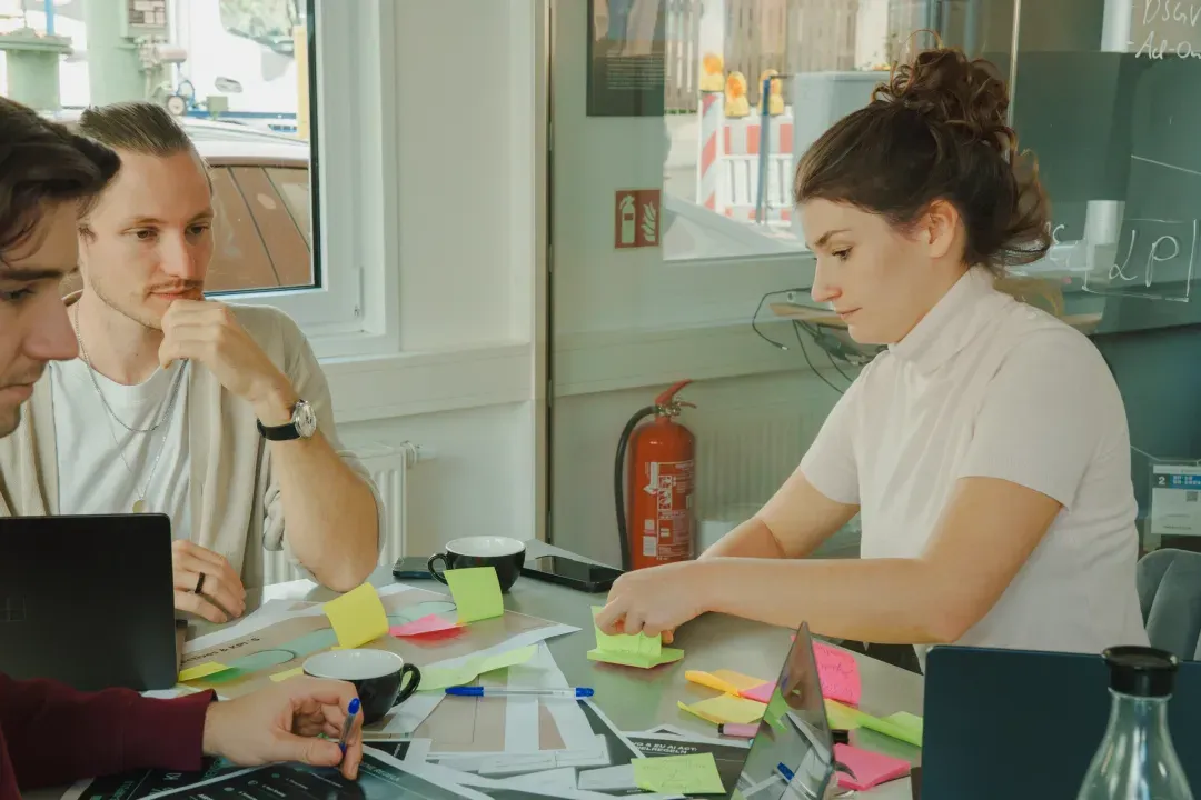 Ein Team arbeitet gemeinsam an einem Besprechungstisch mit Laptops und Haftnotizen