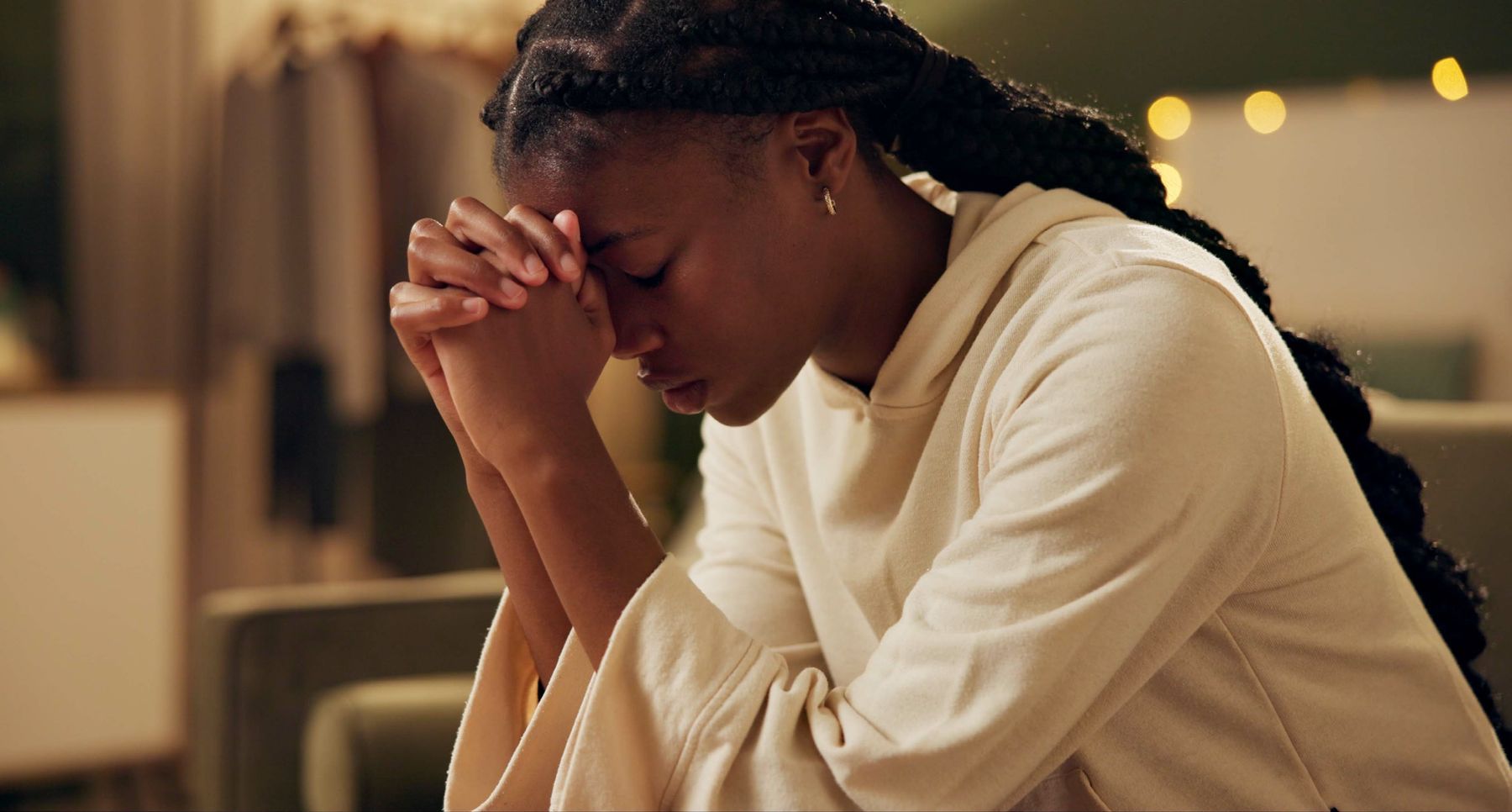 A young woman praying with her hands clasped to her forehead