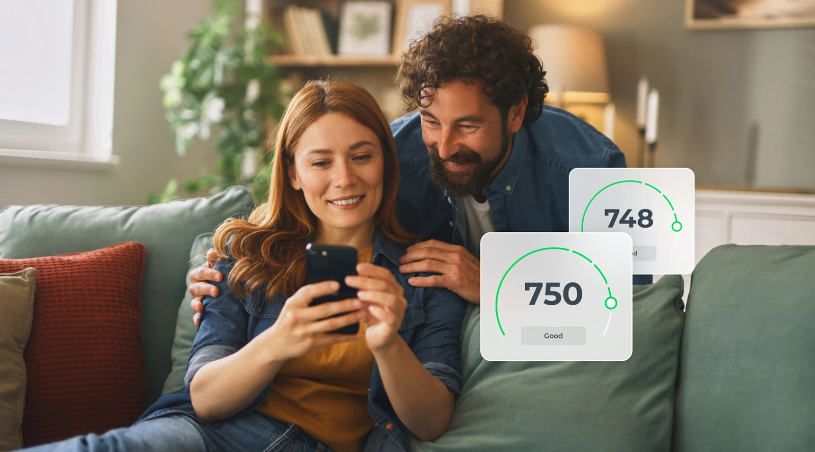 A happy couple sitting on their couch with the woman showing her husband her phone with good credit scores popping out