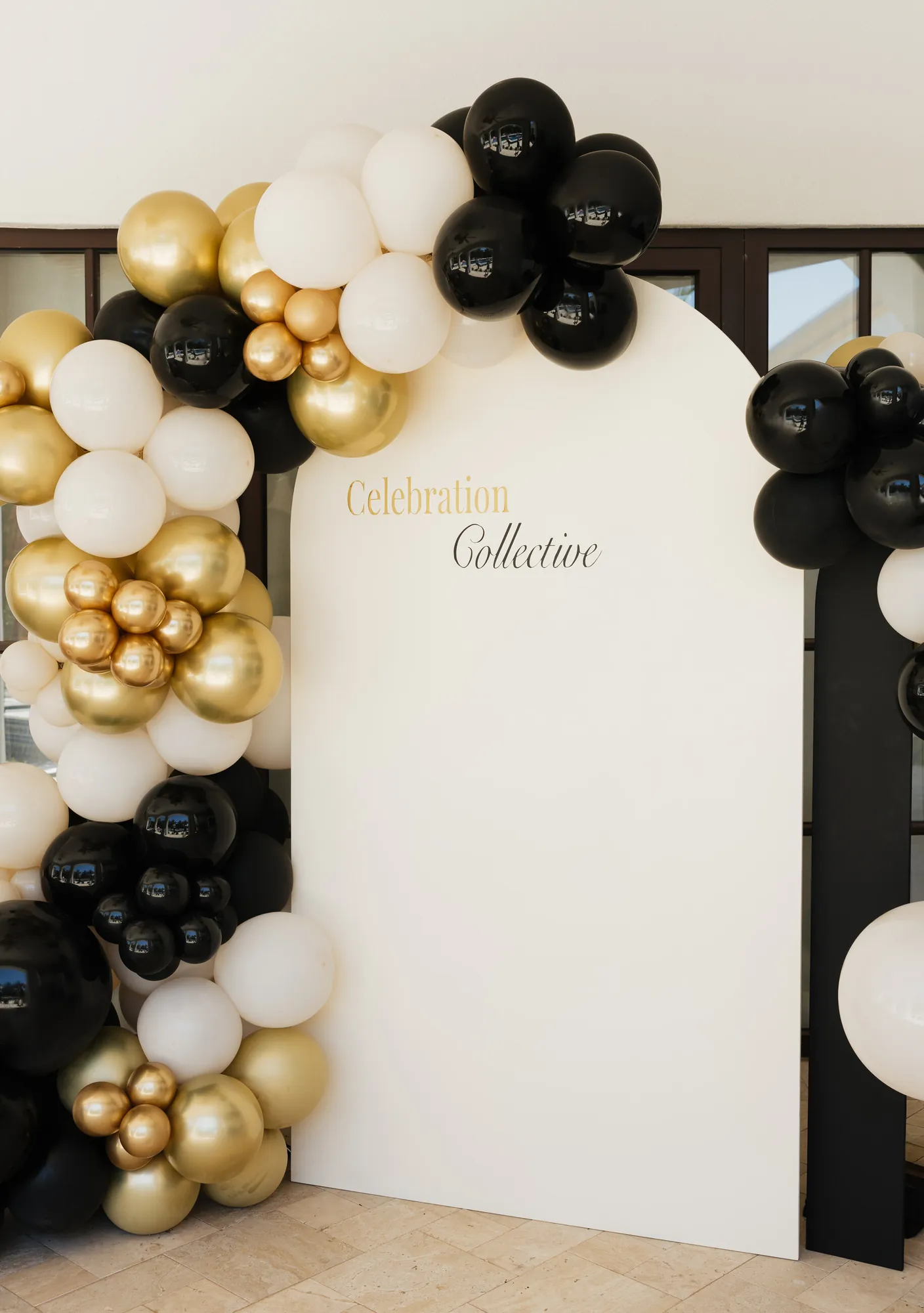 Black, gold and cream balloon garland on a Celebration Collective arch