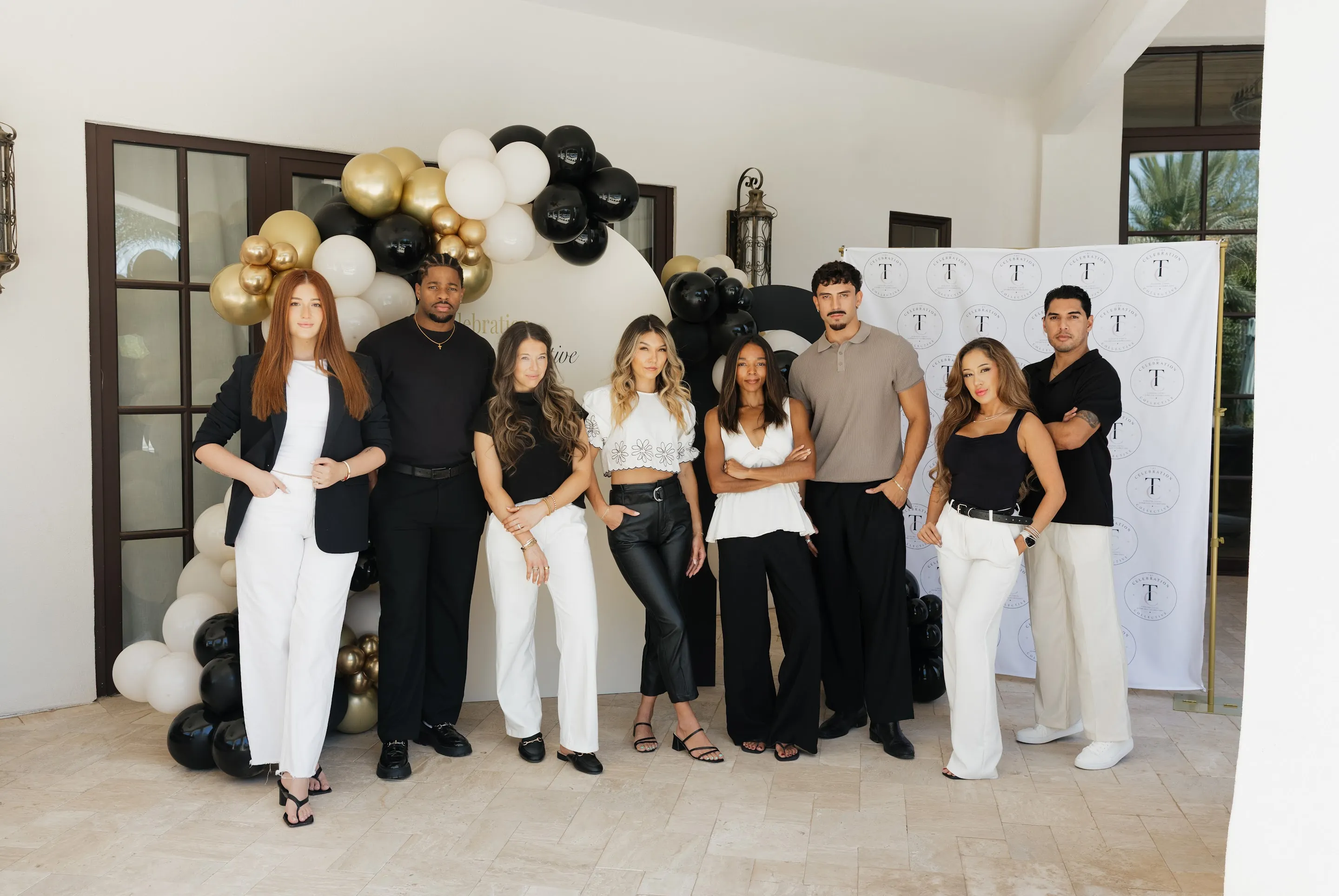 Guests posing in front of a black and gold balloon backdrop at the Collective launch