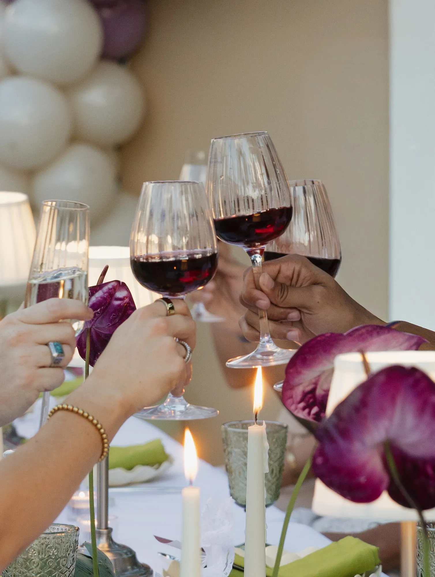 Guests raising glasses of red wine over a candlelit table