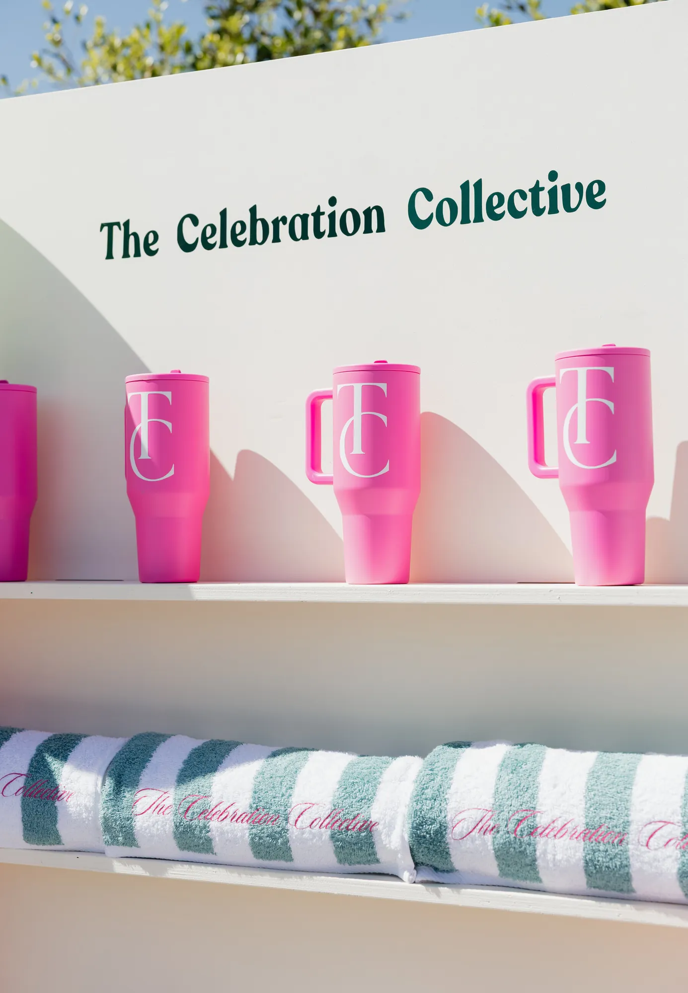 Pink monogram tumblers on a shelf above striped towels