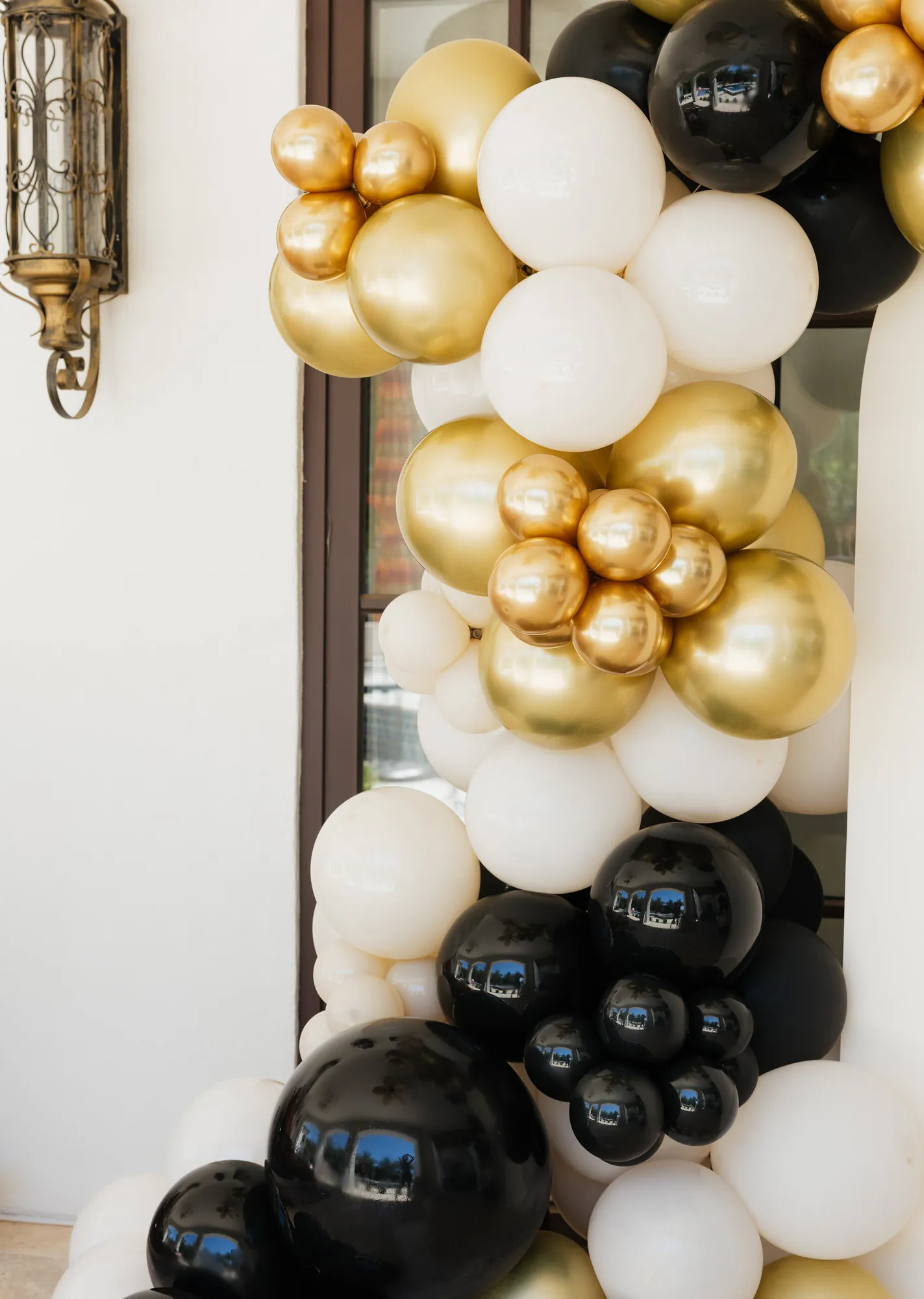 Gold, black and cream balloon garland beside a lantern at a corporate launch