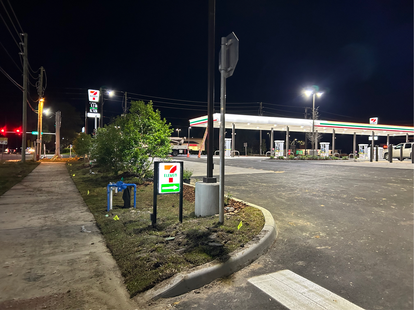 Illuminated 7-Eleven pylon and directional entrance cabinet signs at night