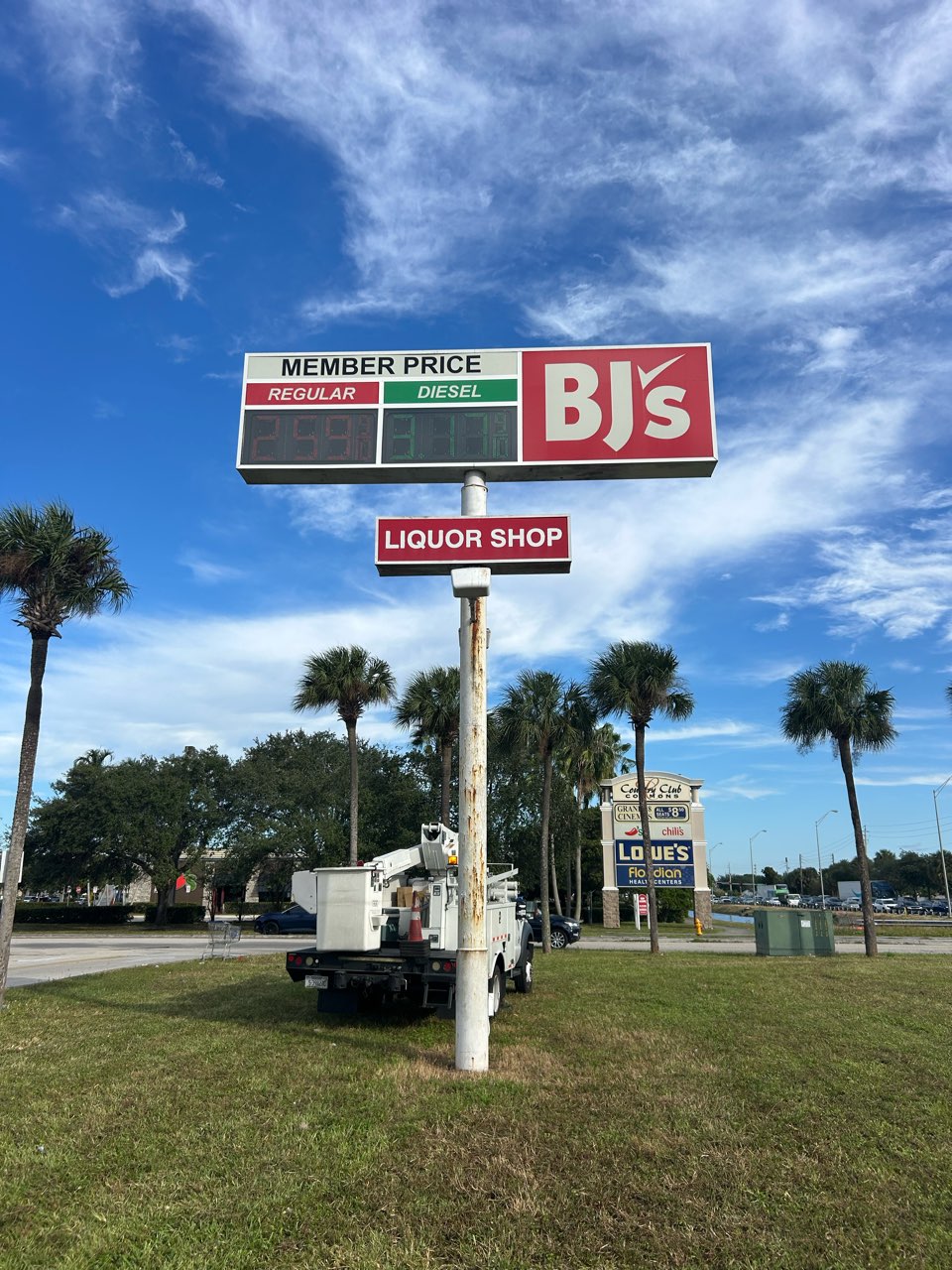 BJ's Wholesale Club pylon sign with fuel price cabinets and Liquor Shop cabinet; service truck on site