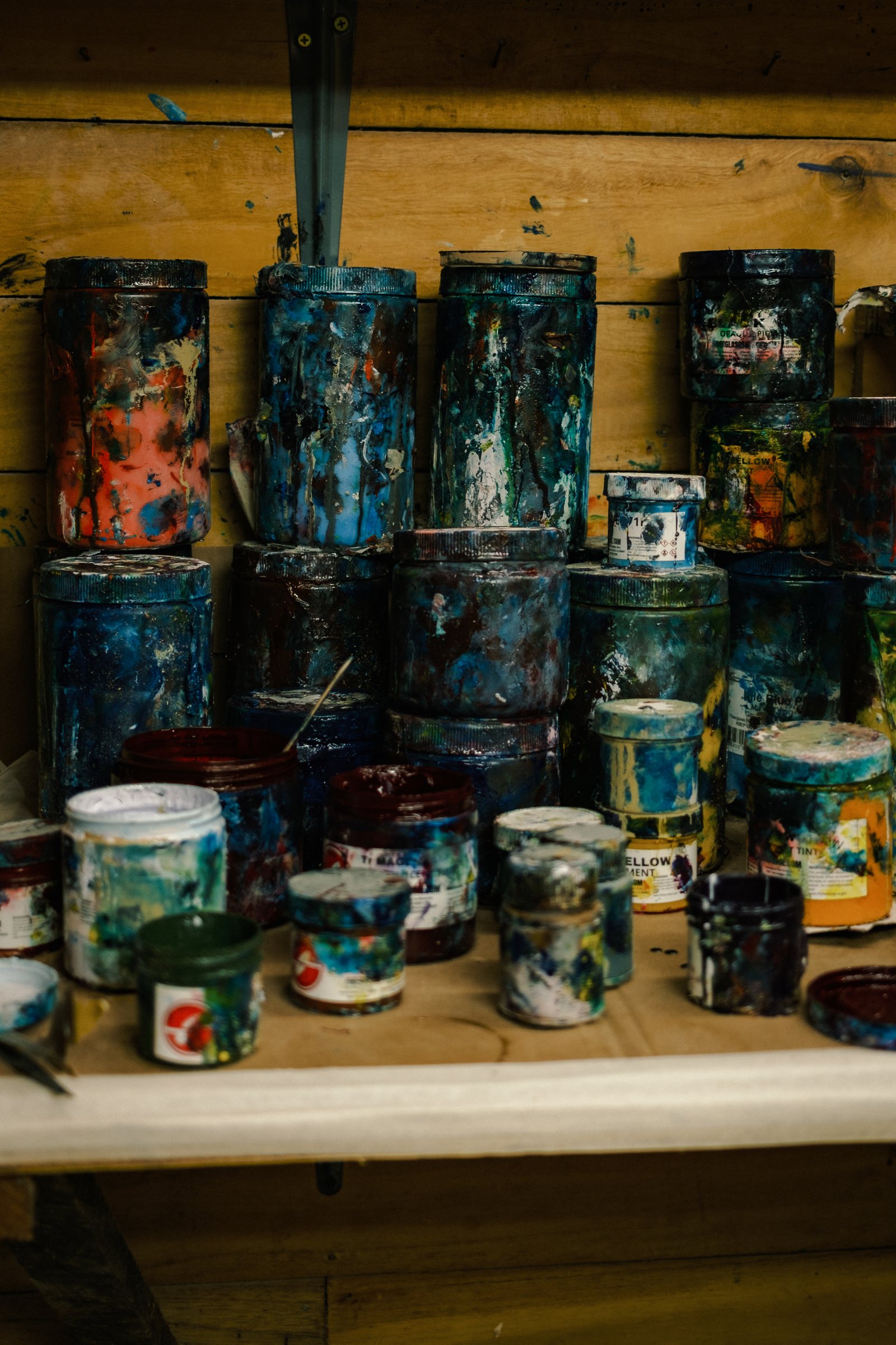 Shelves of paint-splattered resin and pigment tins in the glassing room