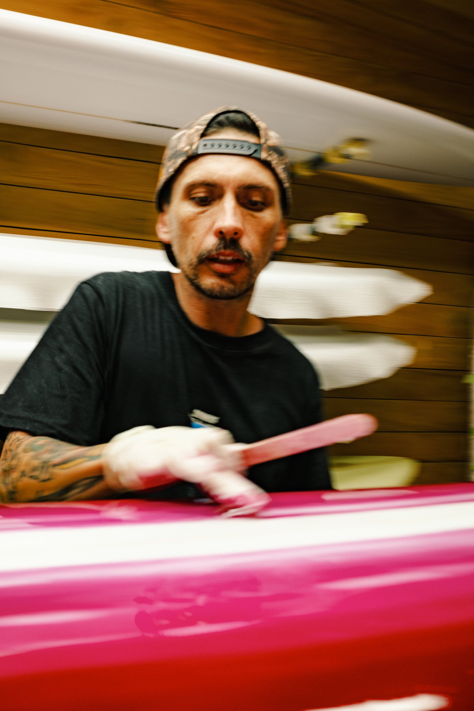Mark Cormack of Nuevo Camino finishing a pink surfboard in the shaping bay at House of Somos