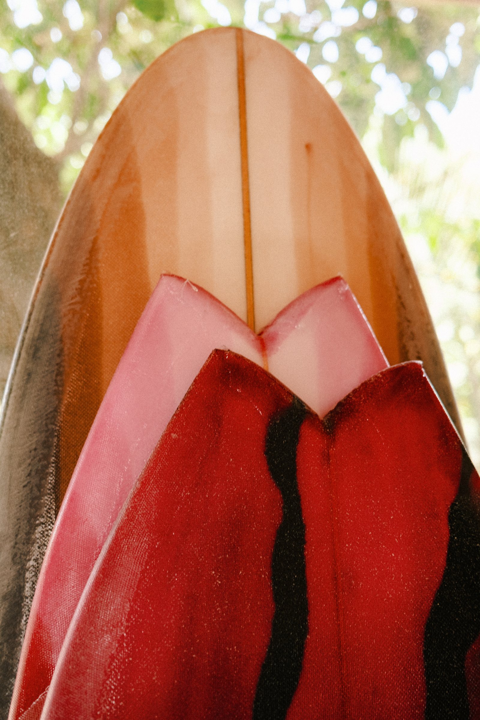 Close-up of a finished red Nuevo Camino surfboard with glassed-on fins