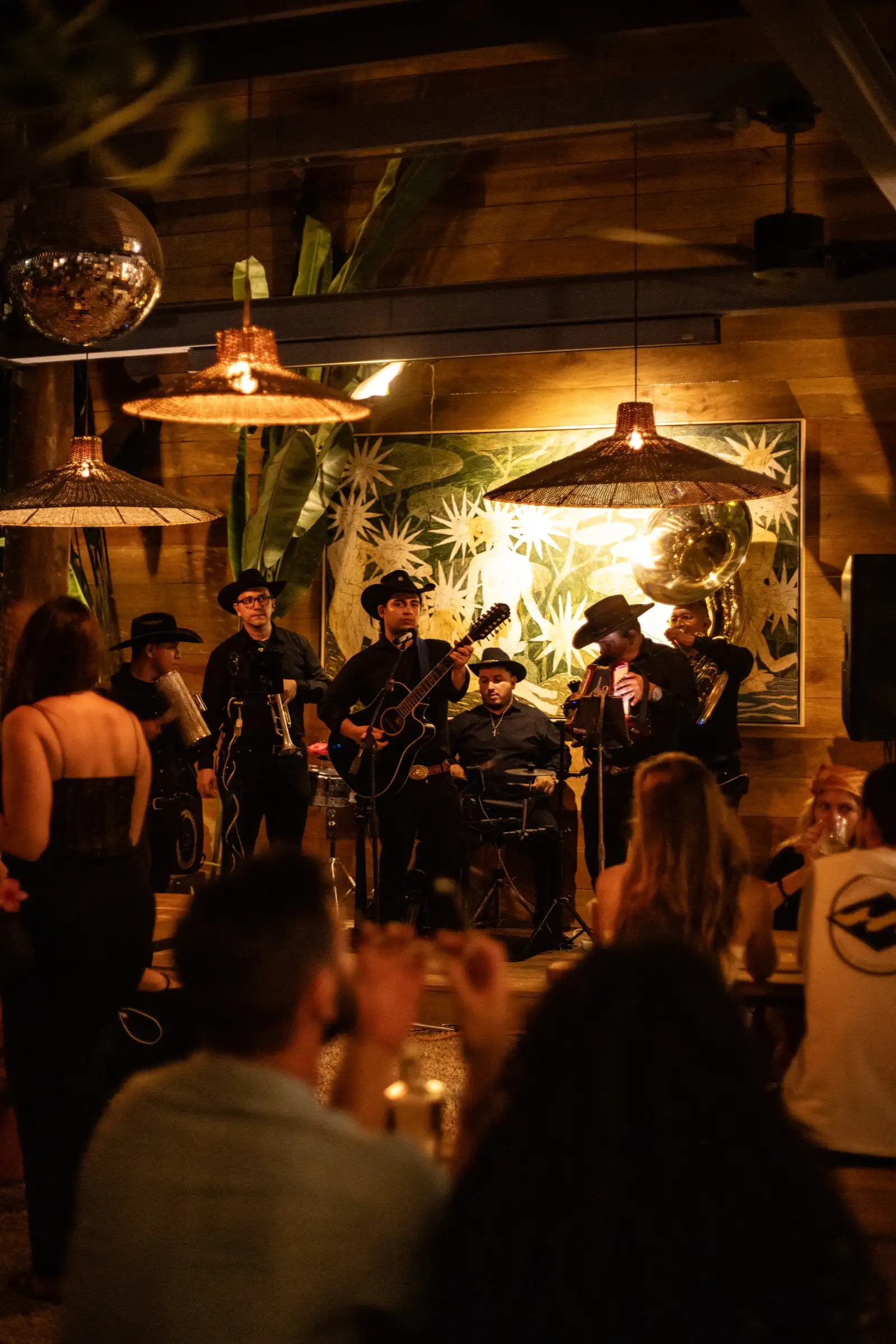Band in cowboy hats playing live for a crowd at night