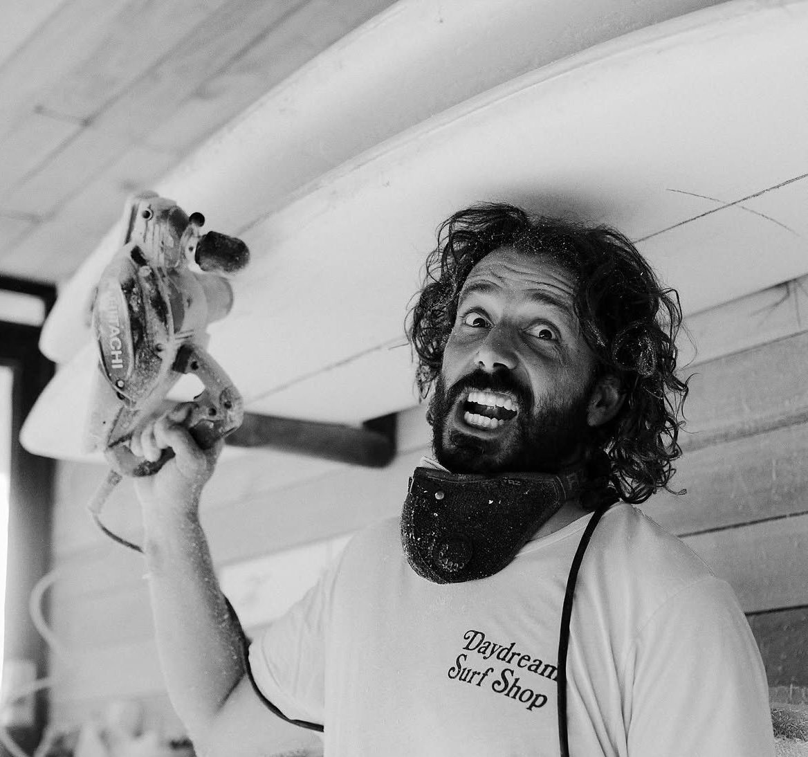 Black-and-white view of a smiling shaper holding a power tool.