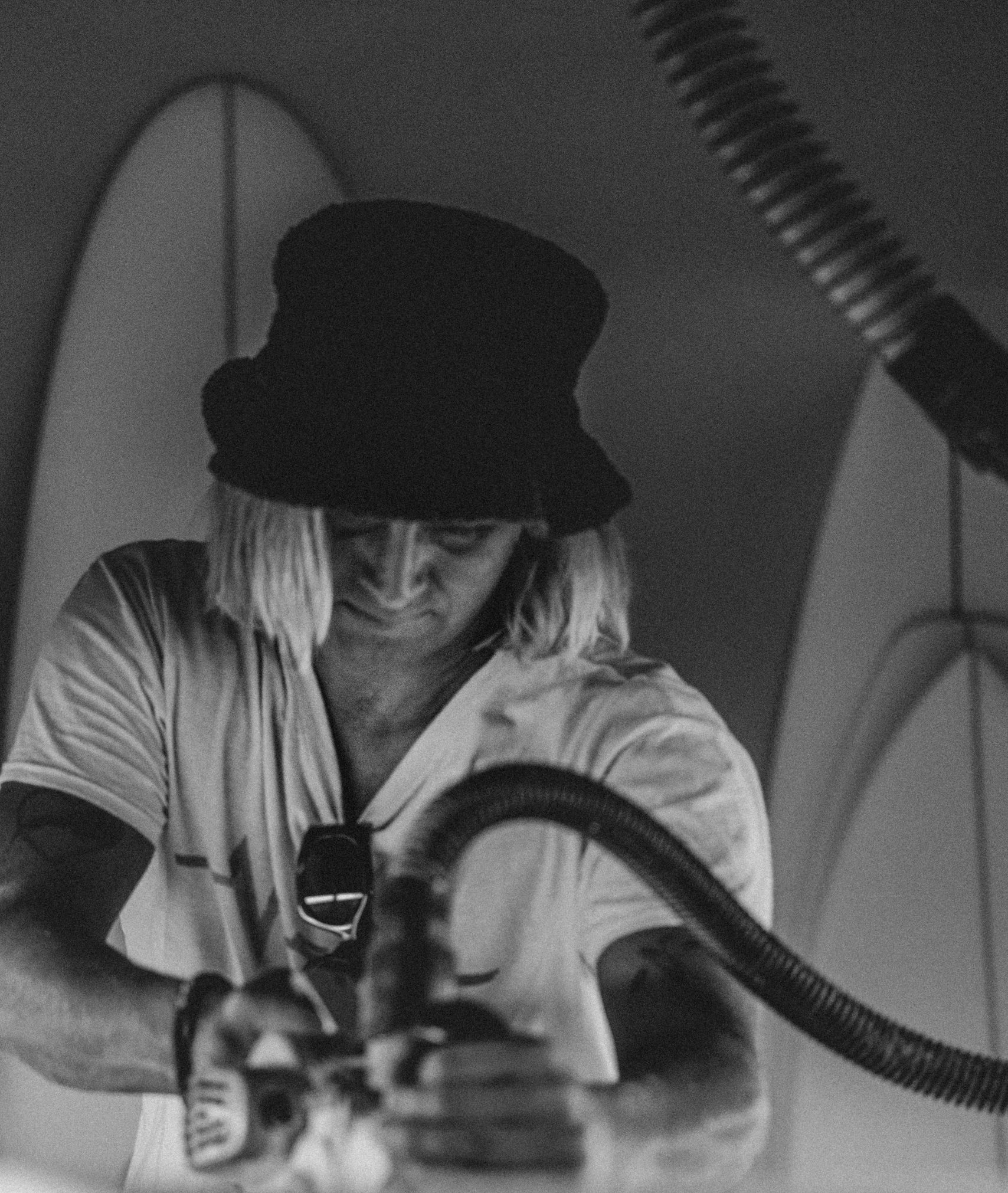 Black-and-white view of a shaper using a power tool on a surfboard.