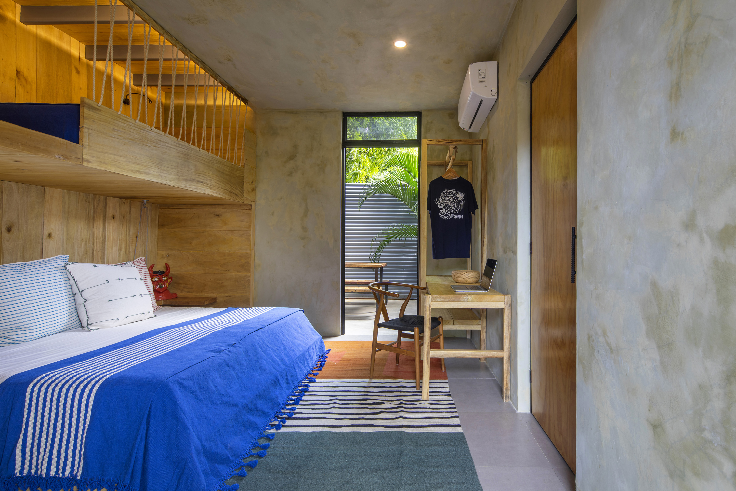 A king bed with blue bedding beside concrete walls and wooden cabinetry.