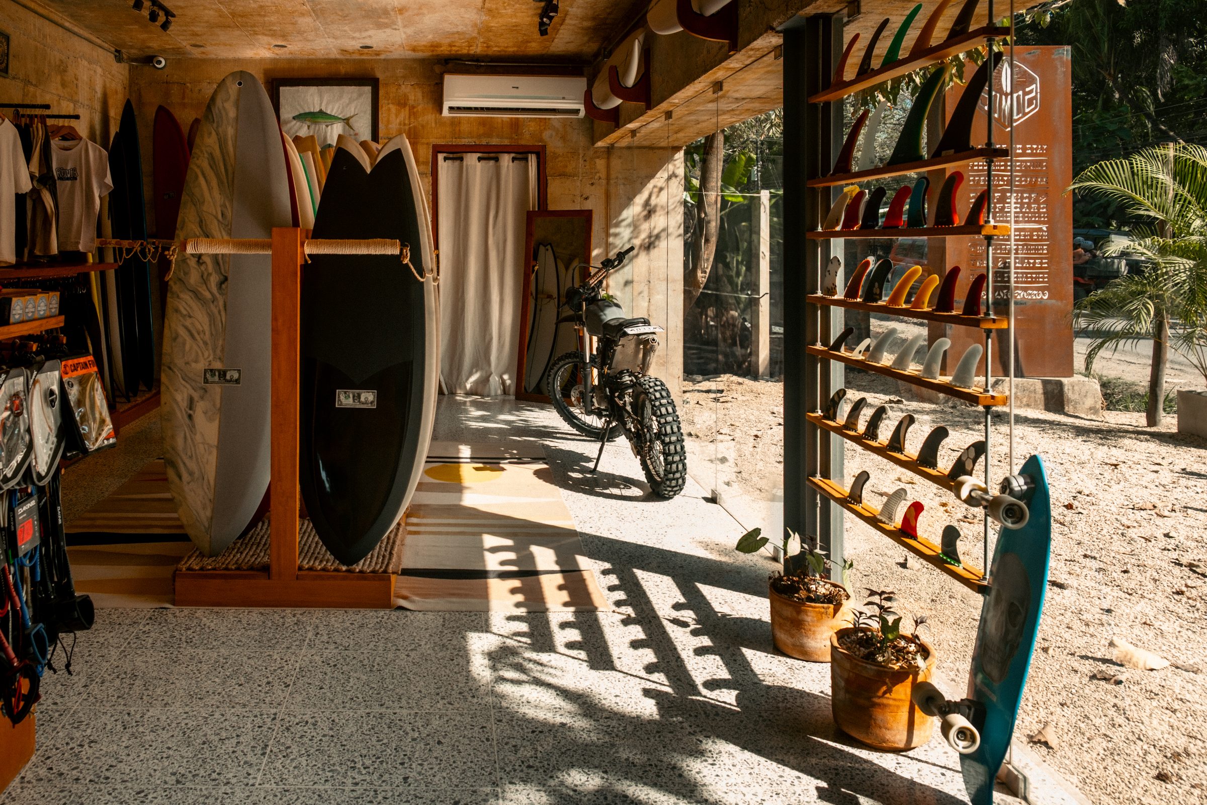 Somos surf shop entrance with surfboards, fins and a motorbike in the sun
