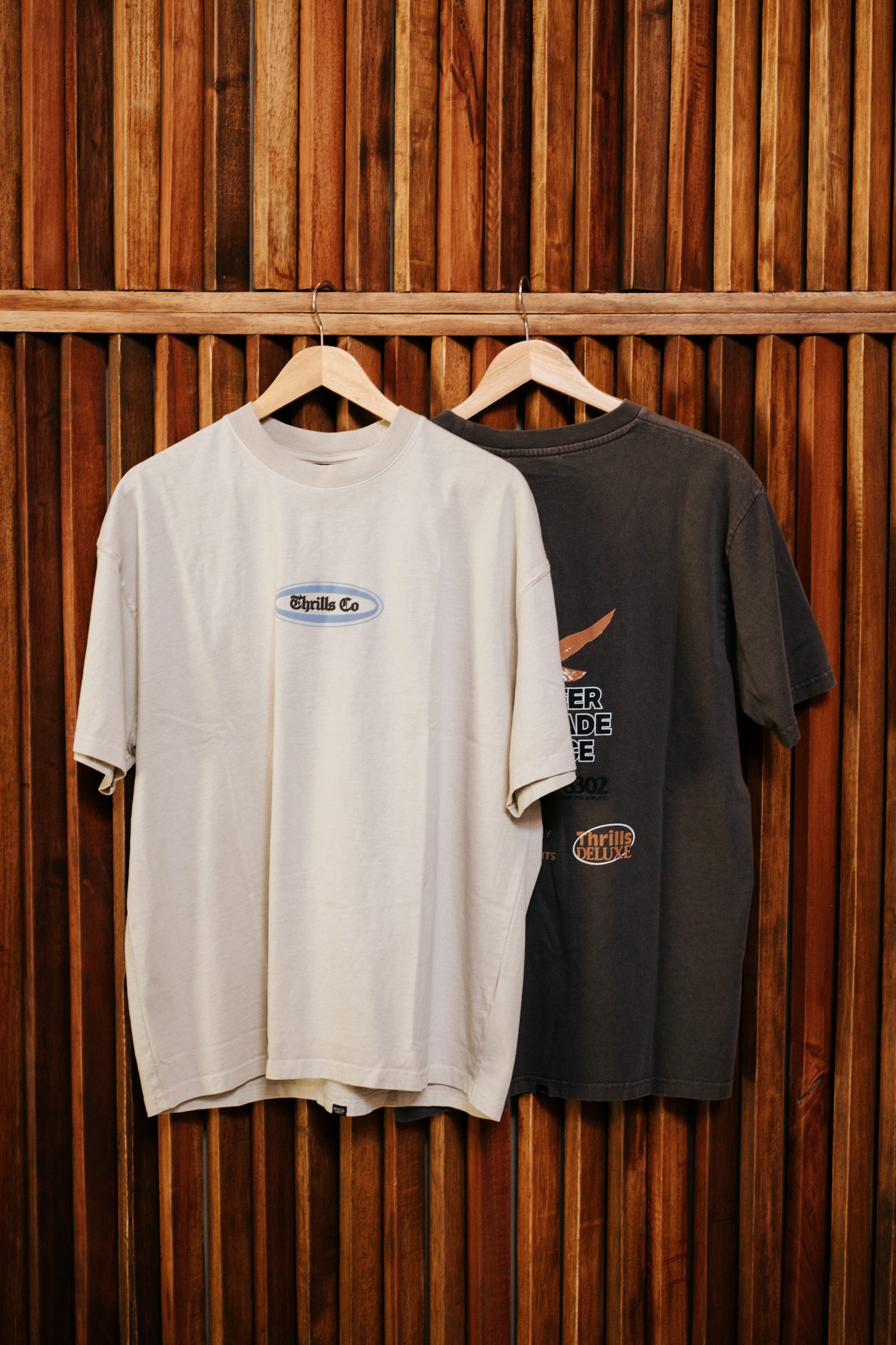 Somos t-shirts hanging against a wooden slat wall