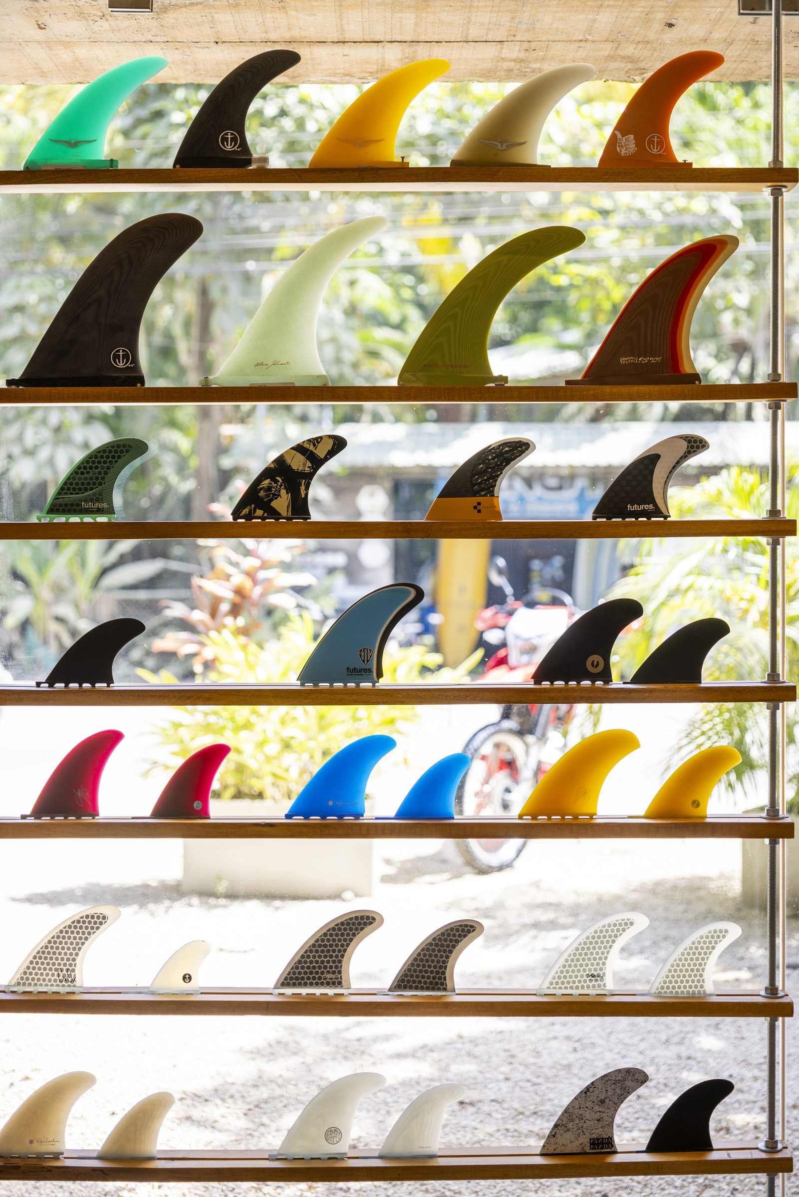 Wall of colorful surfboard fins on wooden shelves