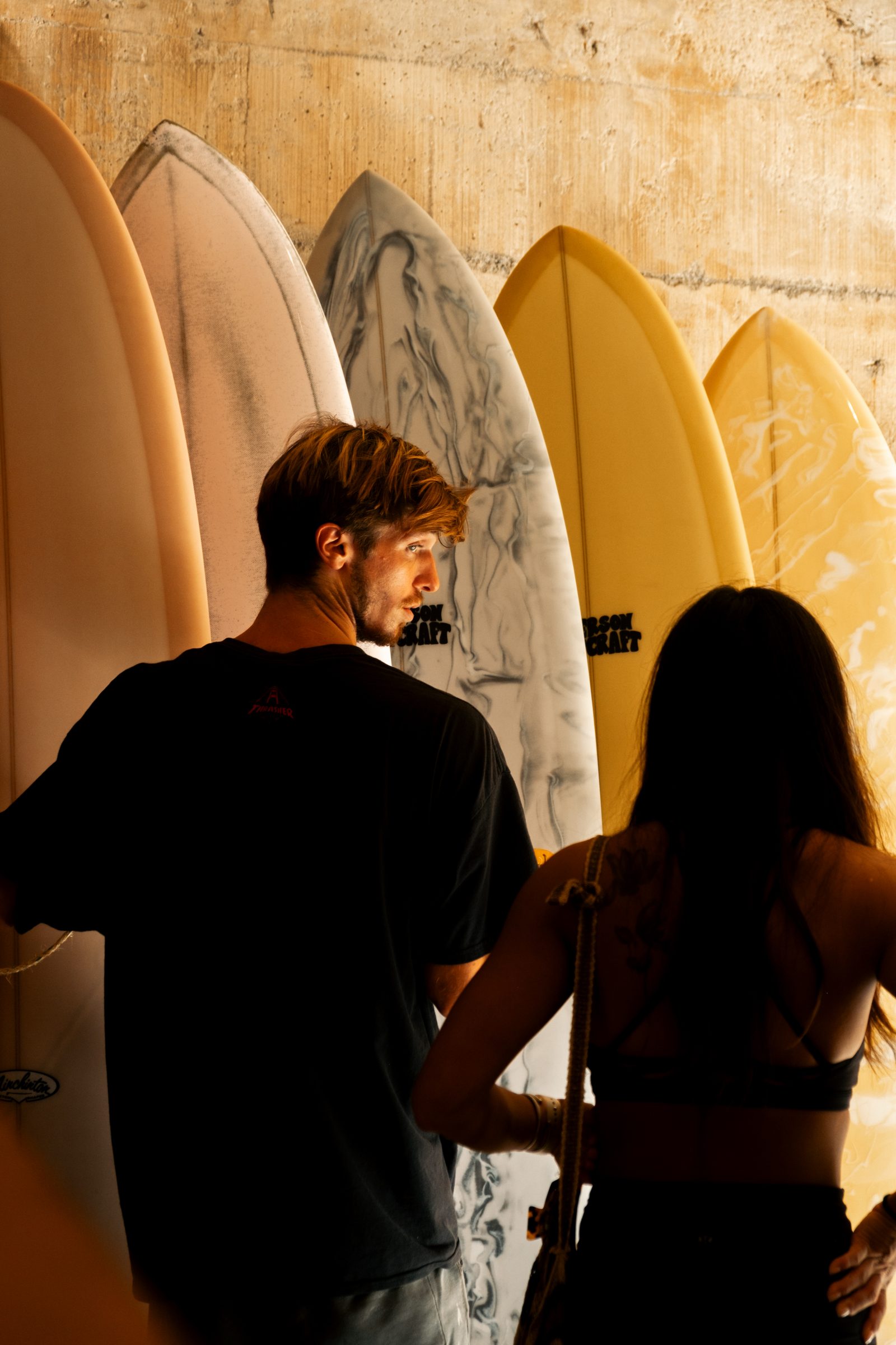 Two people browsing surfboards at the Somos shop