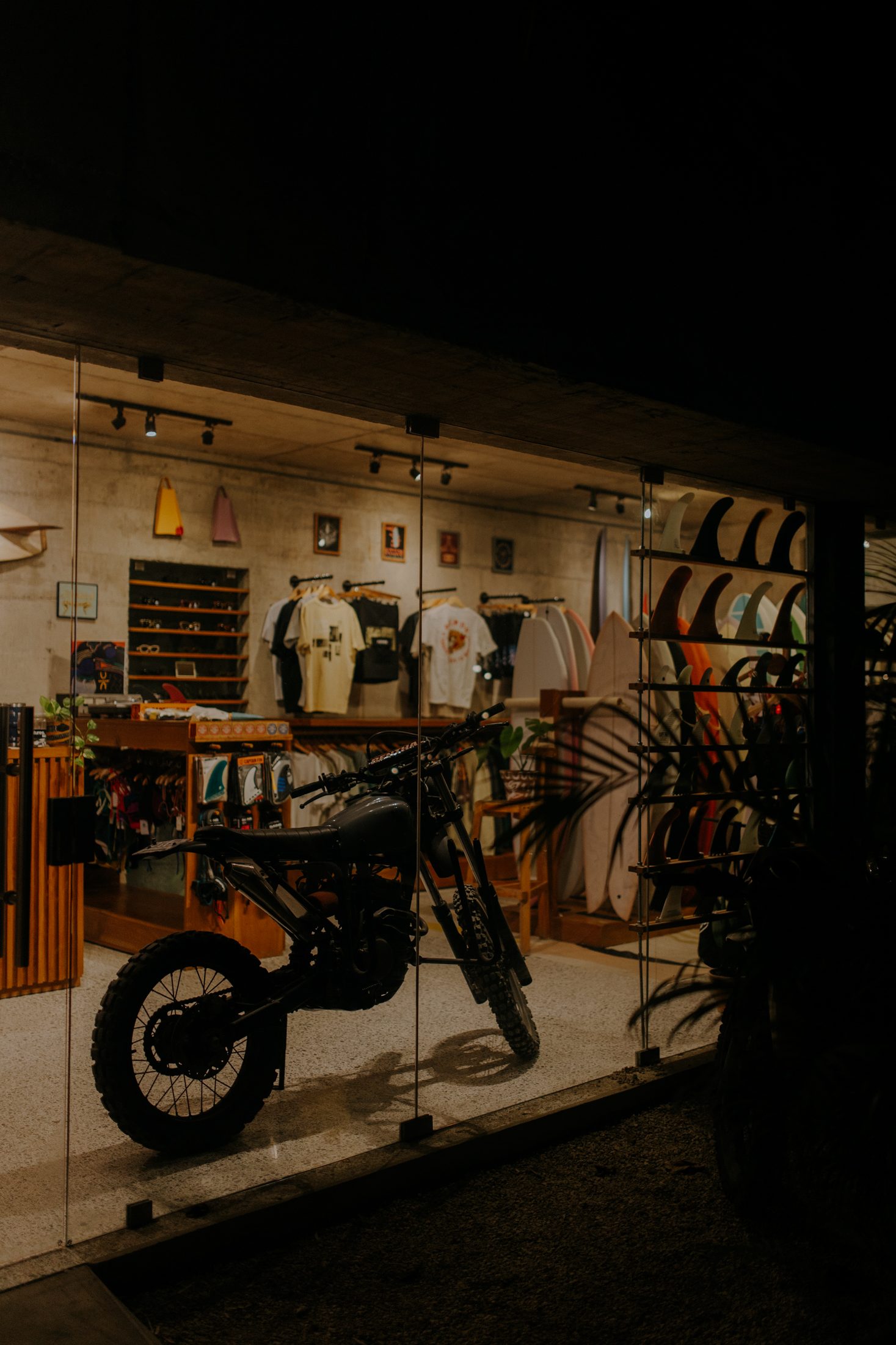 The Somos shop glowing at night with a motorbike in the window