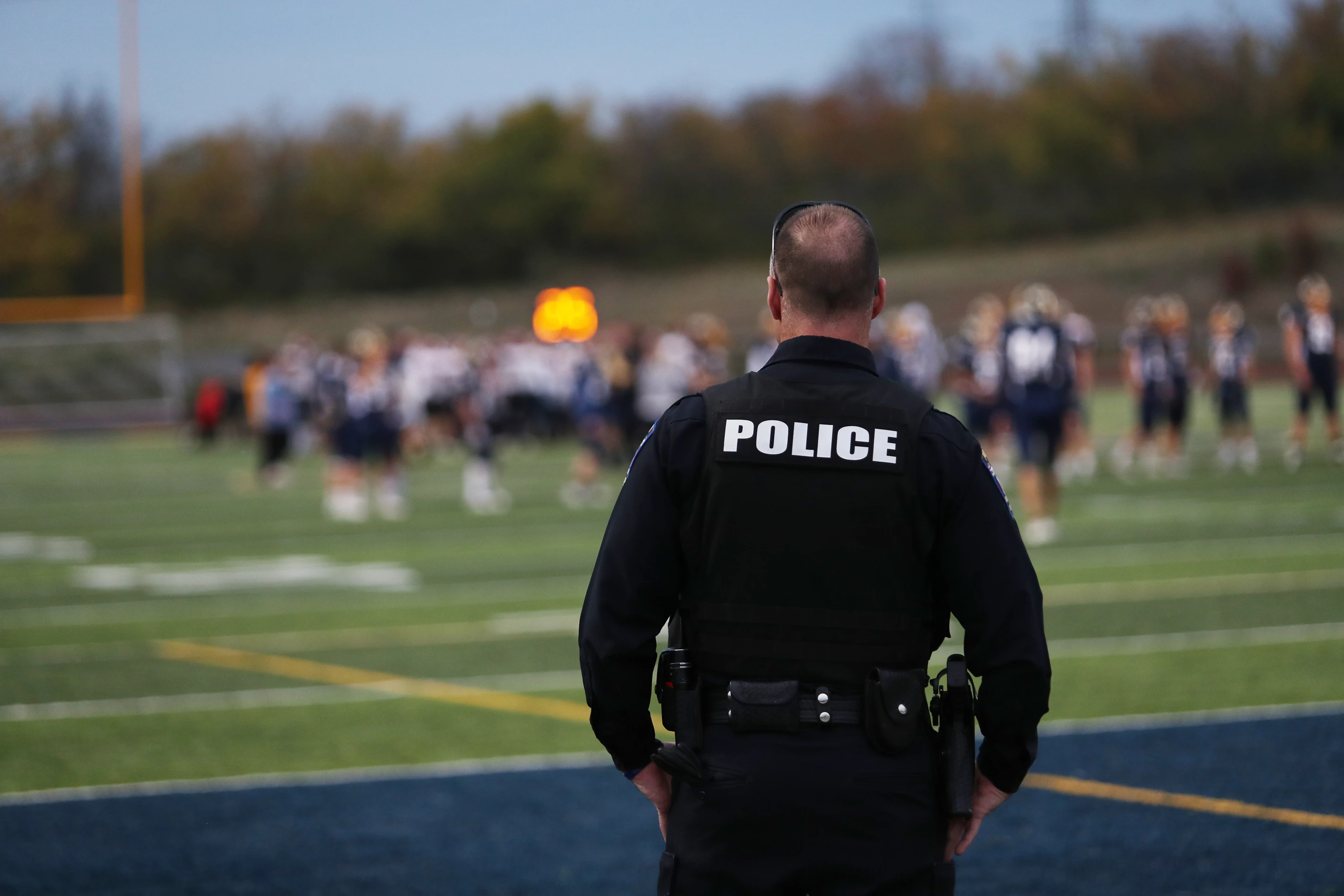 Police officer watching a youth football game from the sideline