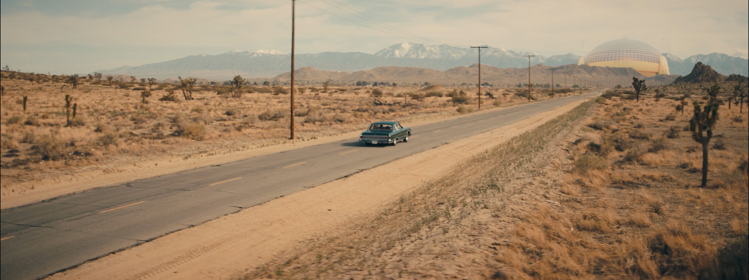 Neo-Dome — car on a desert road approaching the dome