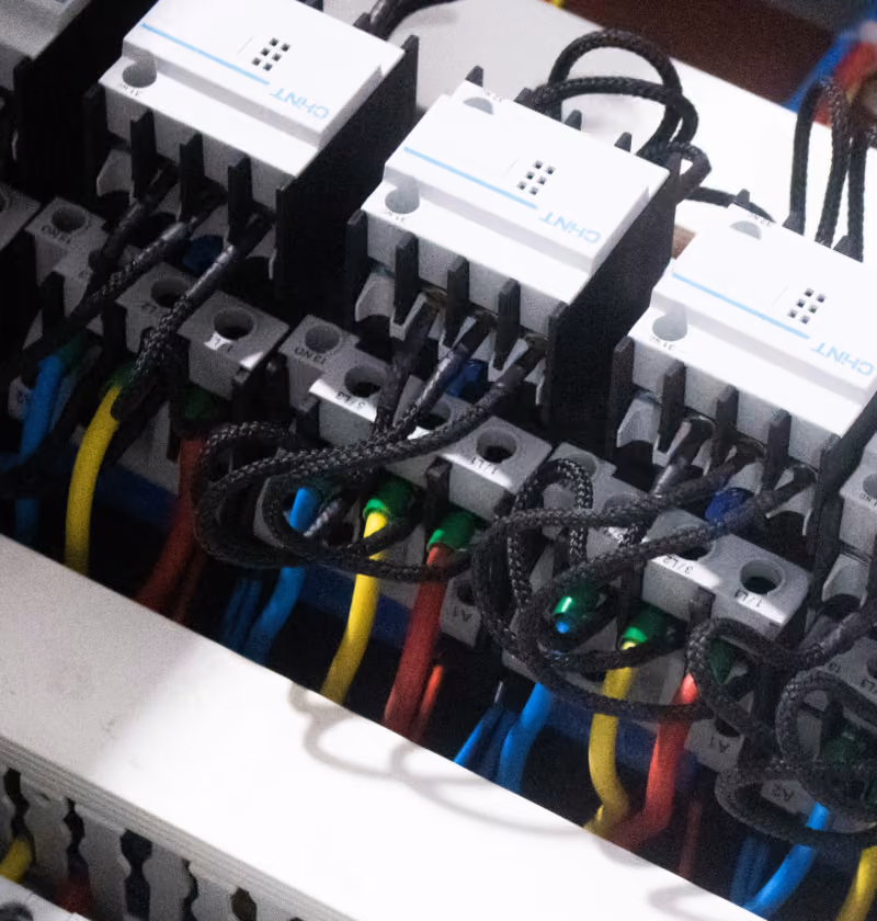 Close-up of electrical wiring connected to three white CHINT branded contactor switches, with multiple colored wires including yellow, blue, red, and green attached to the terminals.