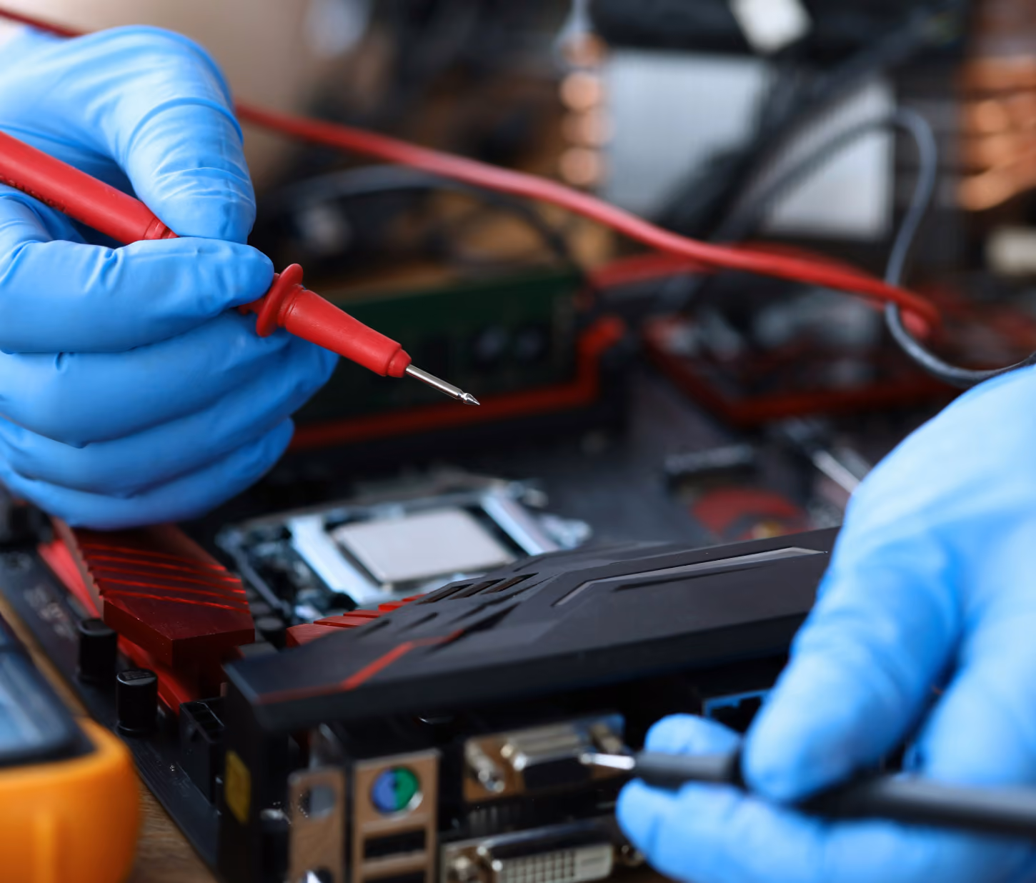 Hands wearing blue gloves using red and black probes to test or repair a computer motherboard with visible CPU socket and ports.
