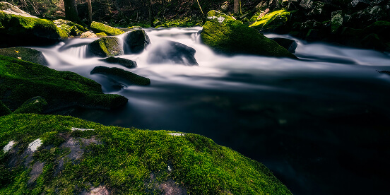 East Tennessee Attractions: A mountain stream running smooth and silky over moss-covered boulders.