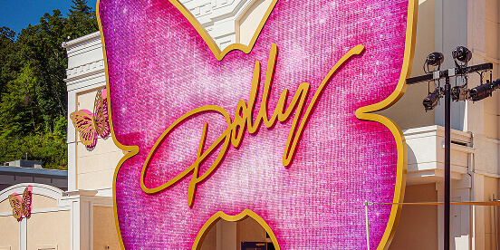 East Tennessee Attractions: A large pink butterfly-shaped sign spelling Dolly in gold script above a park entrance.