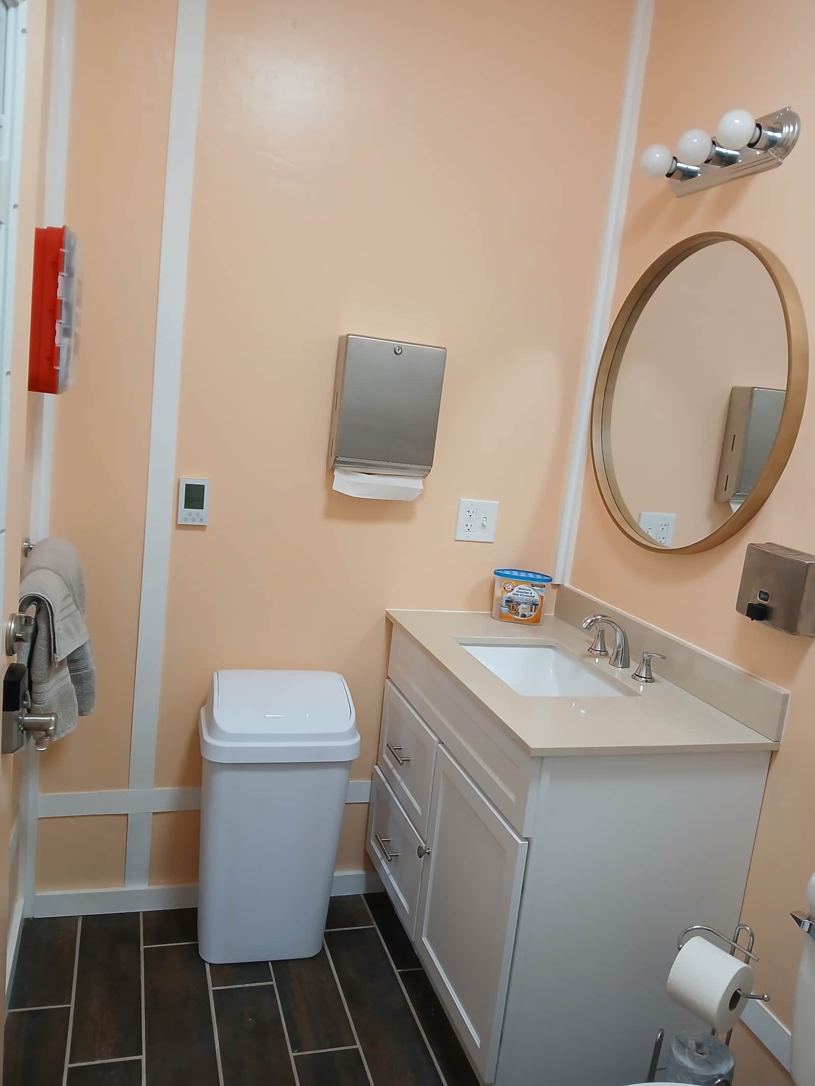 Vacation Rentals in Tennessee: Inside the bathhouse, a vanity with a round mirror, a paper towel dispenser, and a toilet.