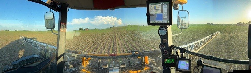 View from the sprayer cab across a field, with the Greeneye display on the dashboard