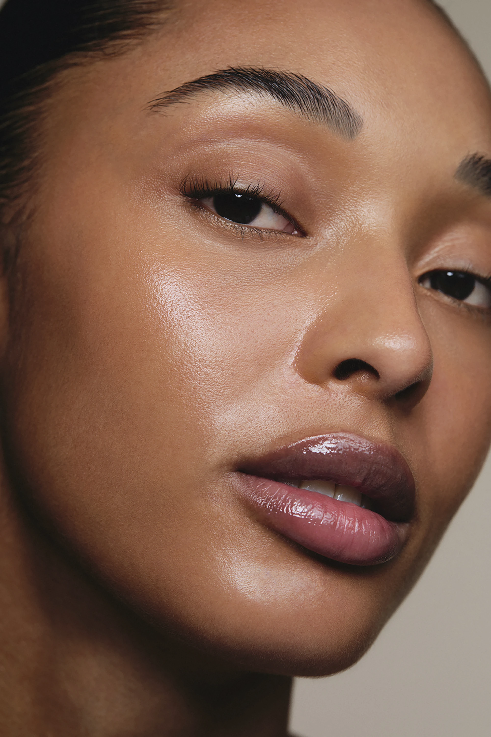 Close-up of a person's face showcasing smooth skin, glossy lips, and well-groomed eyebrows.