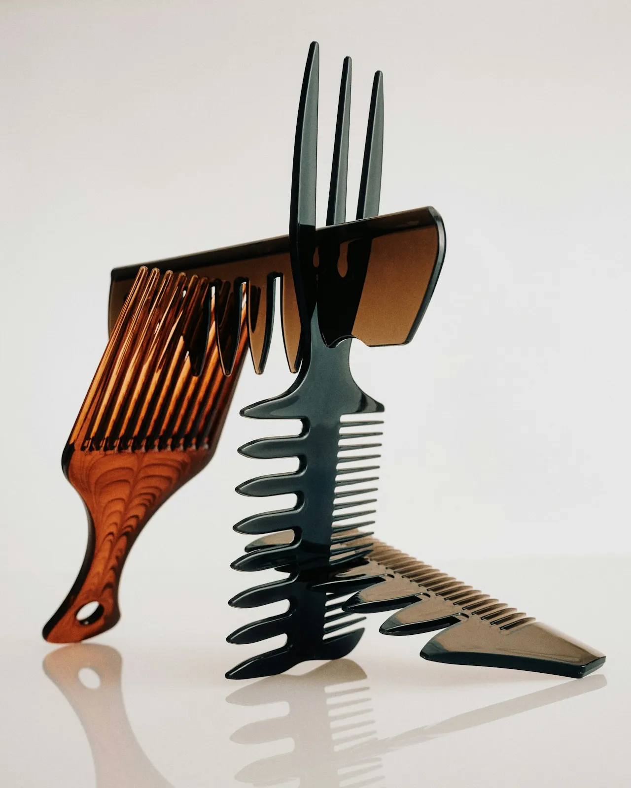 Four hair combs in varying shades of amber and obsidian, precariously balanced and interlocking to form a single, tense structure. The combs are positioned at opposing angles, demonstrating a "system of friction" where the teeth of one tool grip the spine of another to maintain a fragile equilibrium.