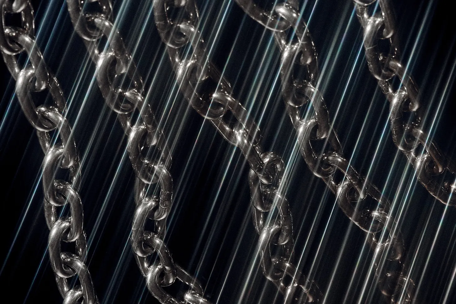 Close-up of multiple transparent chain links hanging against a dark background, crossed by thin diagonal streaks of blue-white light that create a glossy, reflective effect.