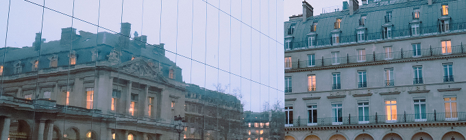 a typical parisian building seen in the reflection of a glass walled building