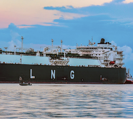 Large LNG tanker ship on calm water with pastel sky at sunset.