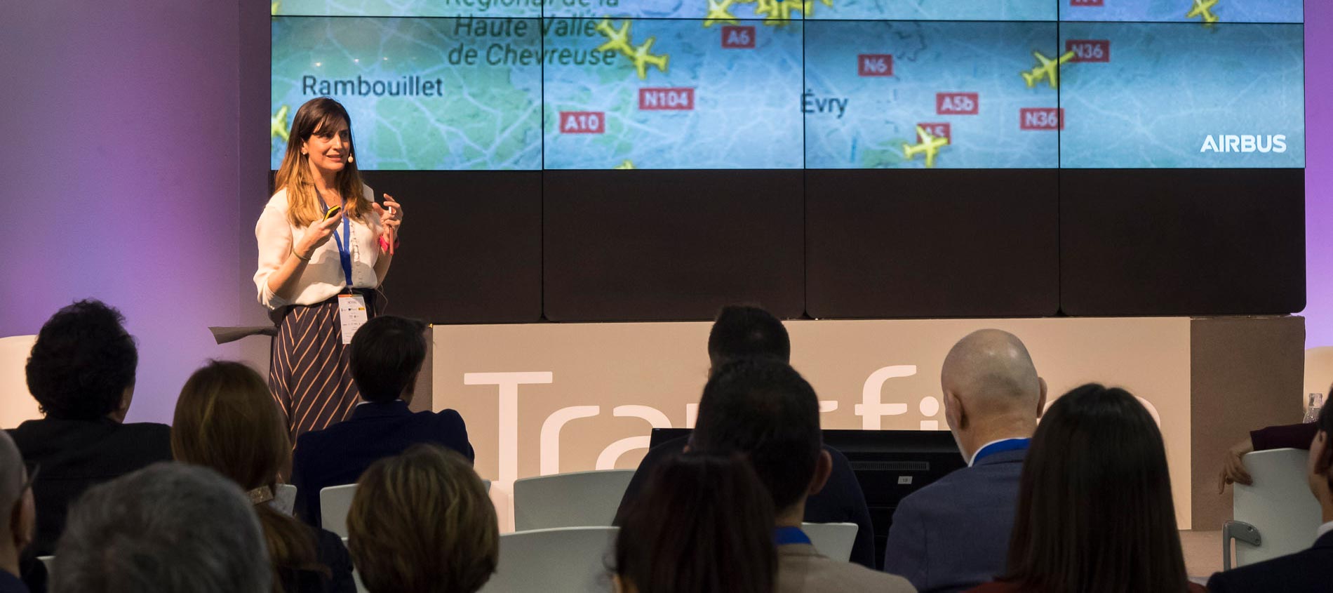 A woman speaking during a conference, the audience is listening attentively