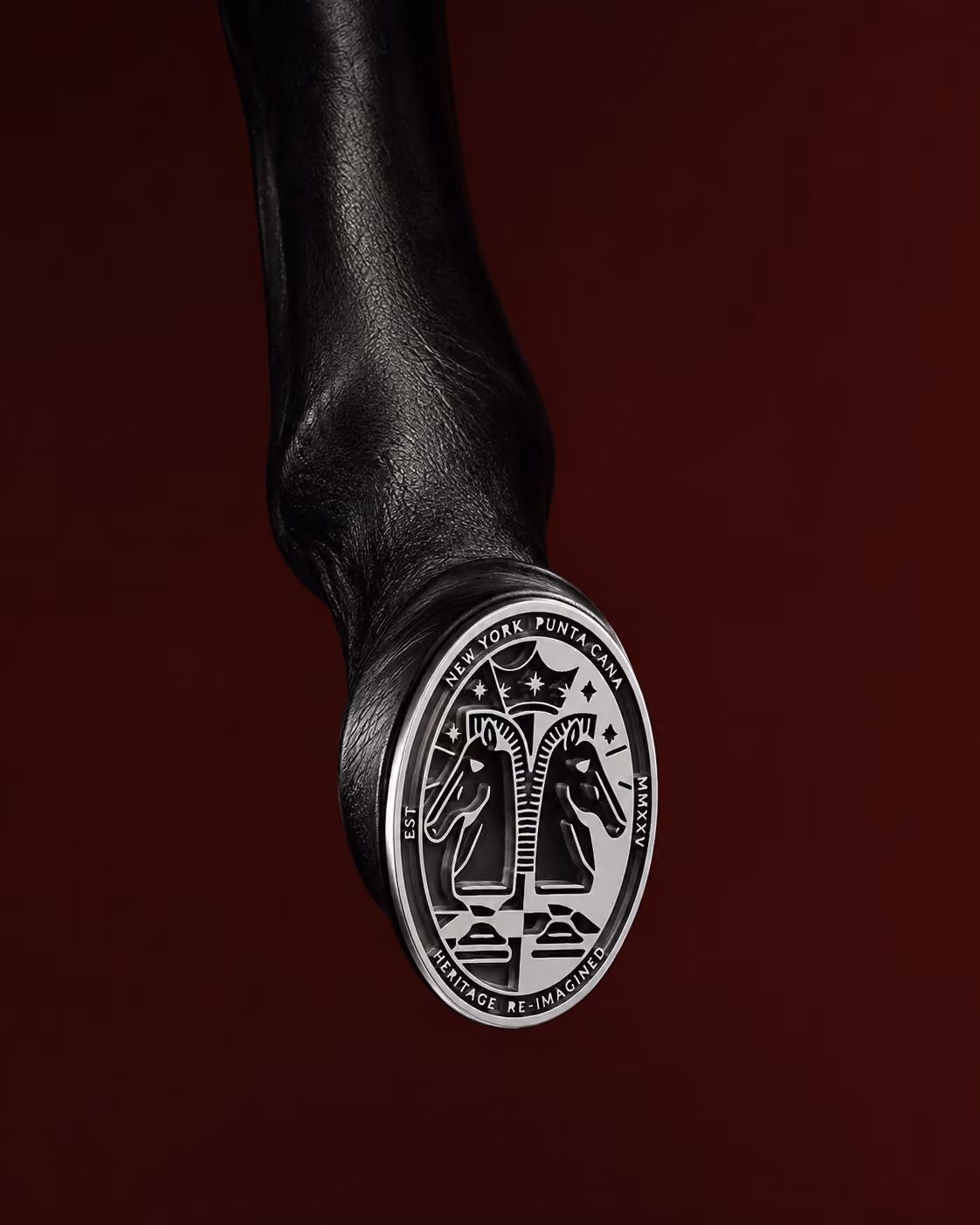 Silver seal engraved with two horses, set on black leather against deep red