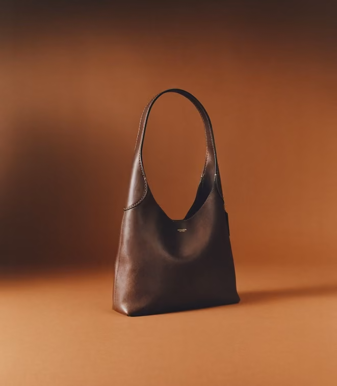 Brown leather hobo handbag against an orange studio backdrop