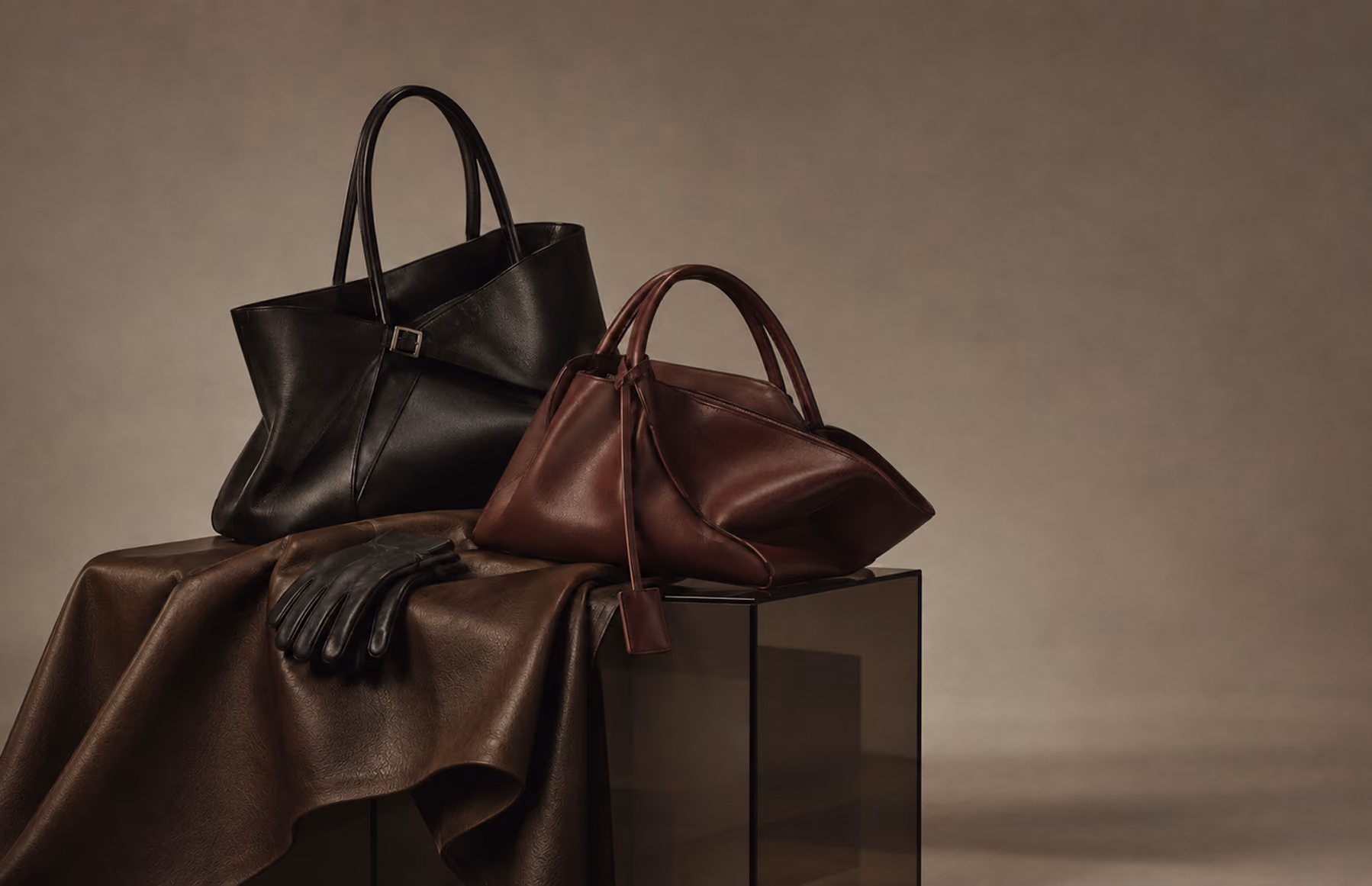 Black and burgundy leather handbags resting on draped leather