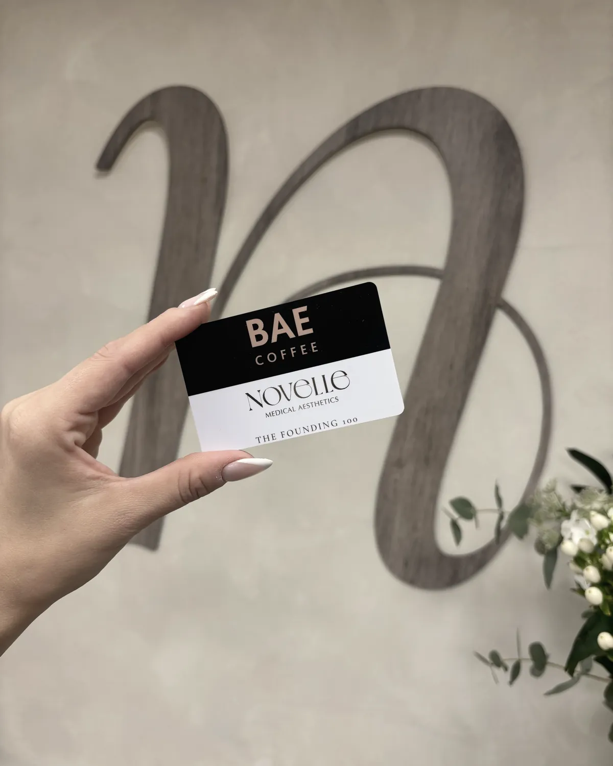 A BAE Coffee gift card for Founding 100 members, held in front of the Novelle mark